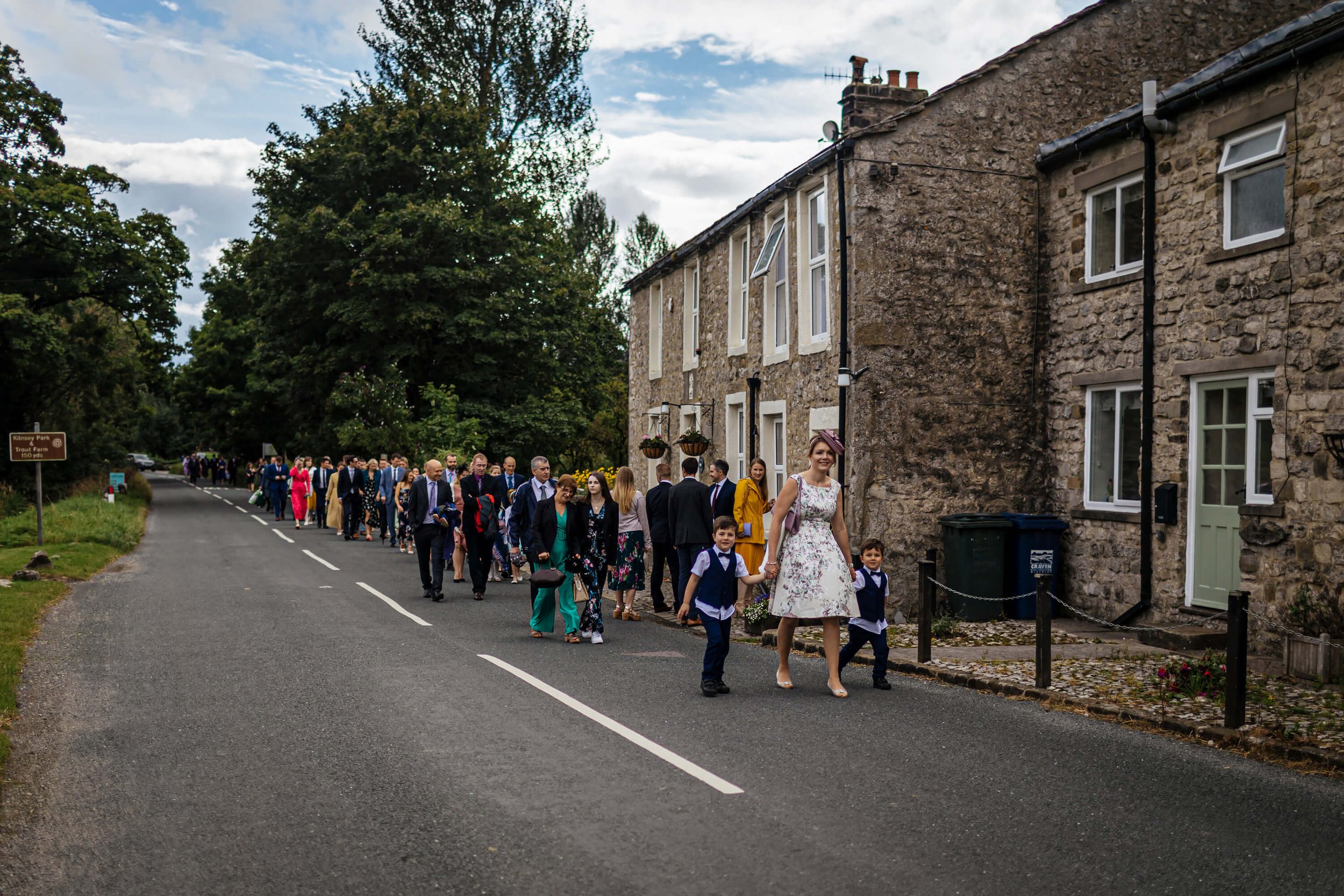 Wedding guests walking through Kilnsey village