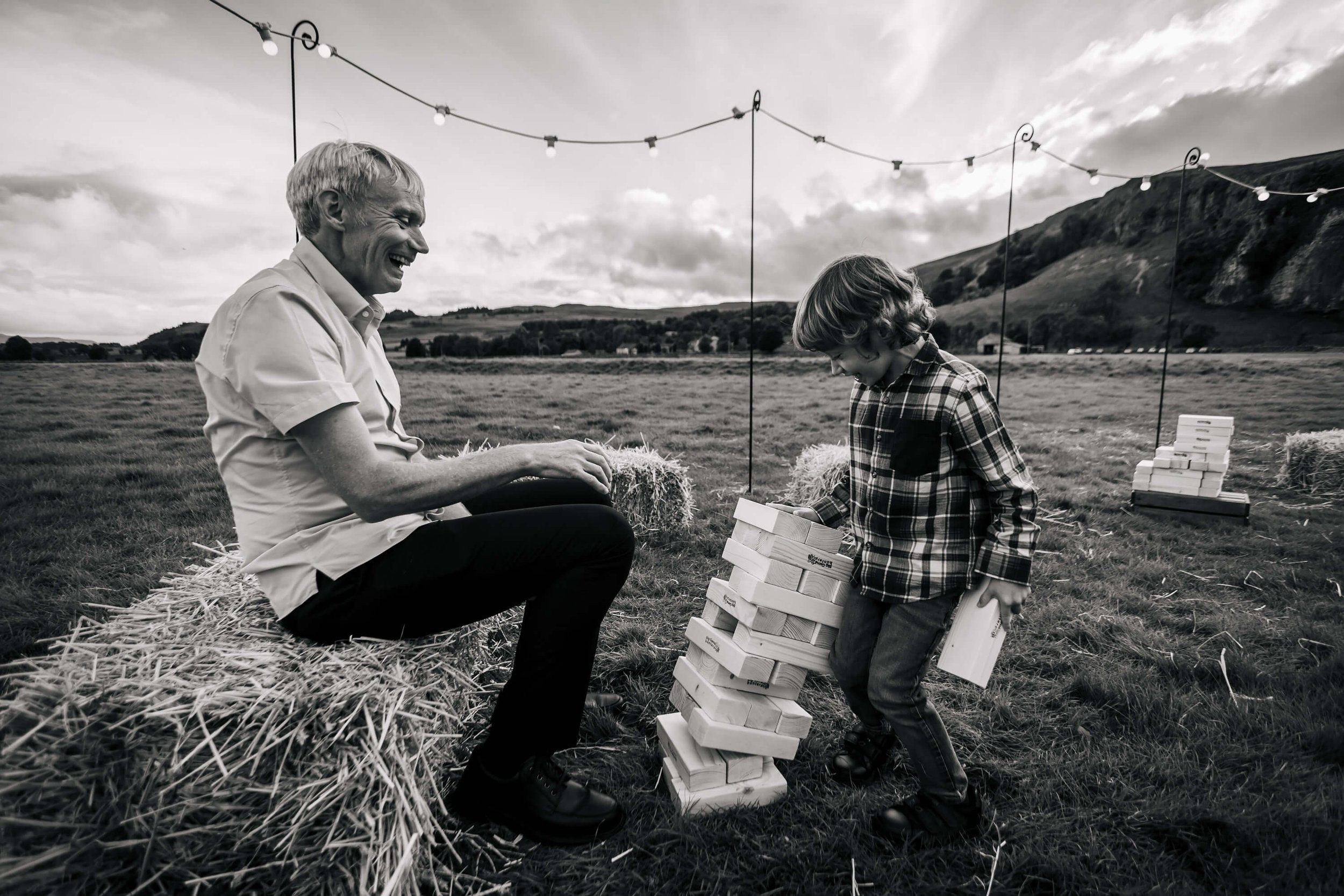 Young boy playing jenga with his dad at a wedding