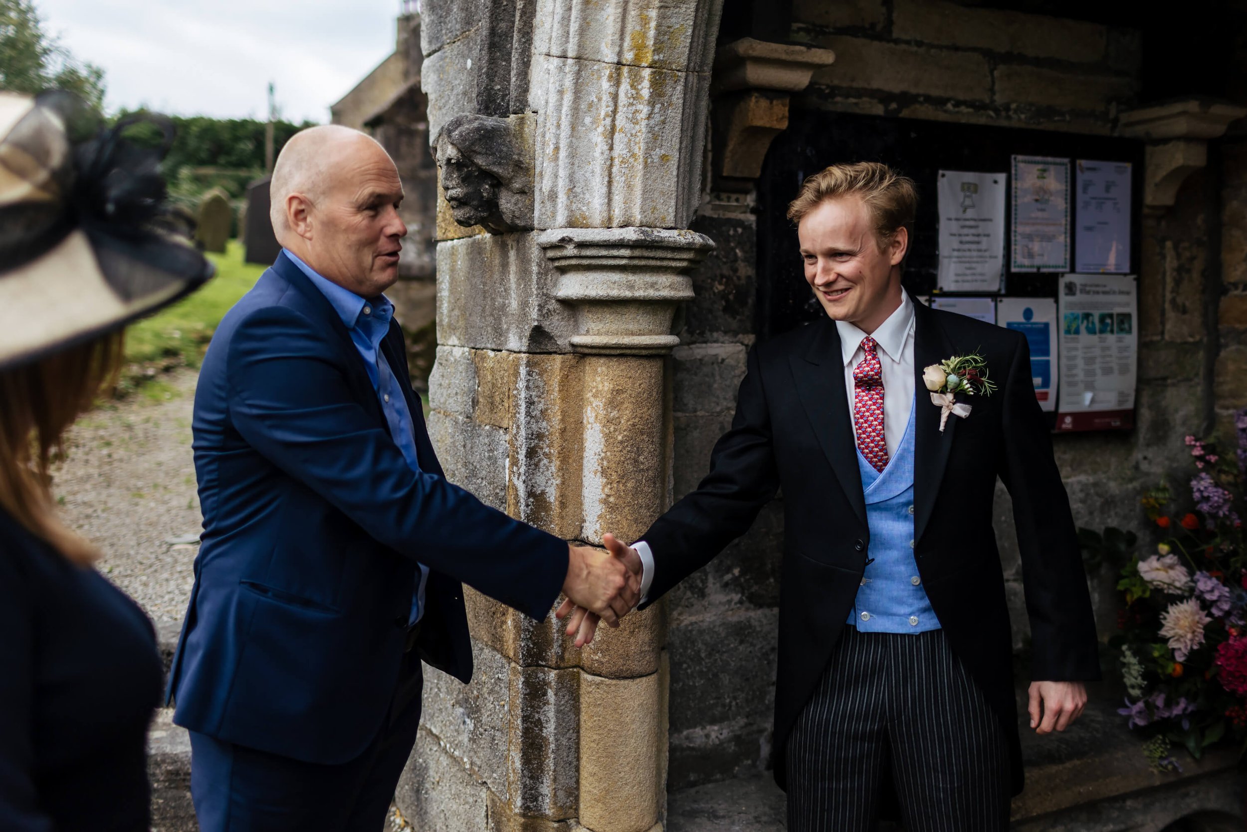 Groom shakes hands with wedding guests at the church