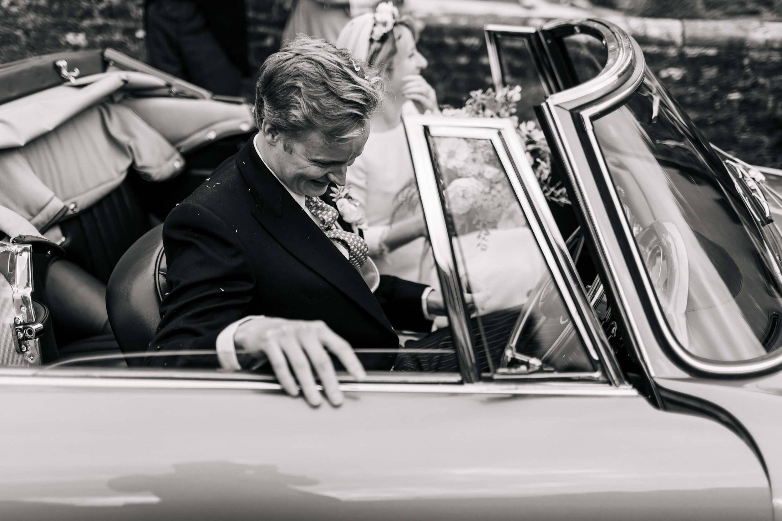 Groom getting into his vintage wedding car