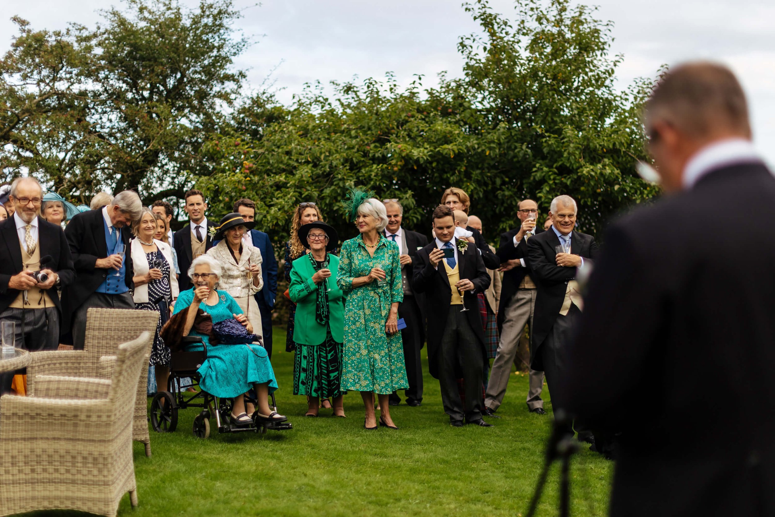 Wedding guests during the speeches in the garden