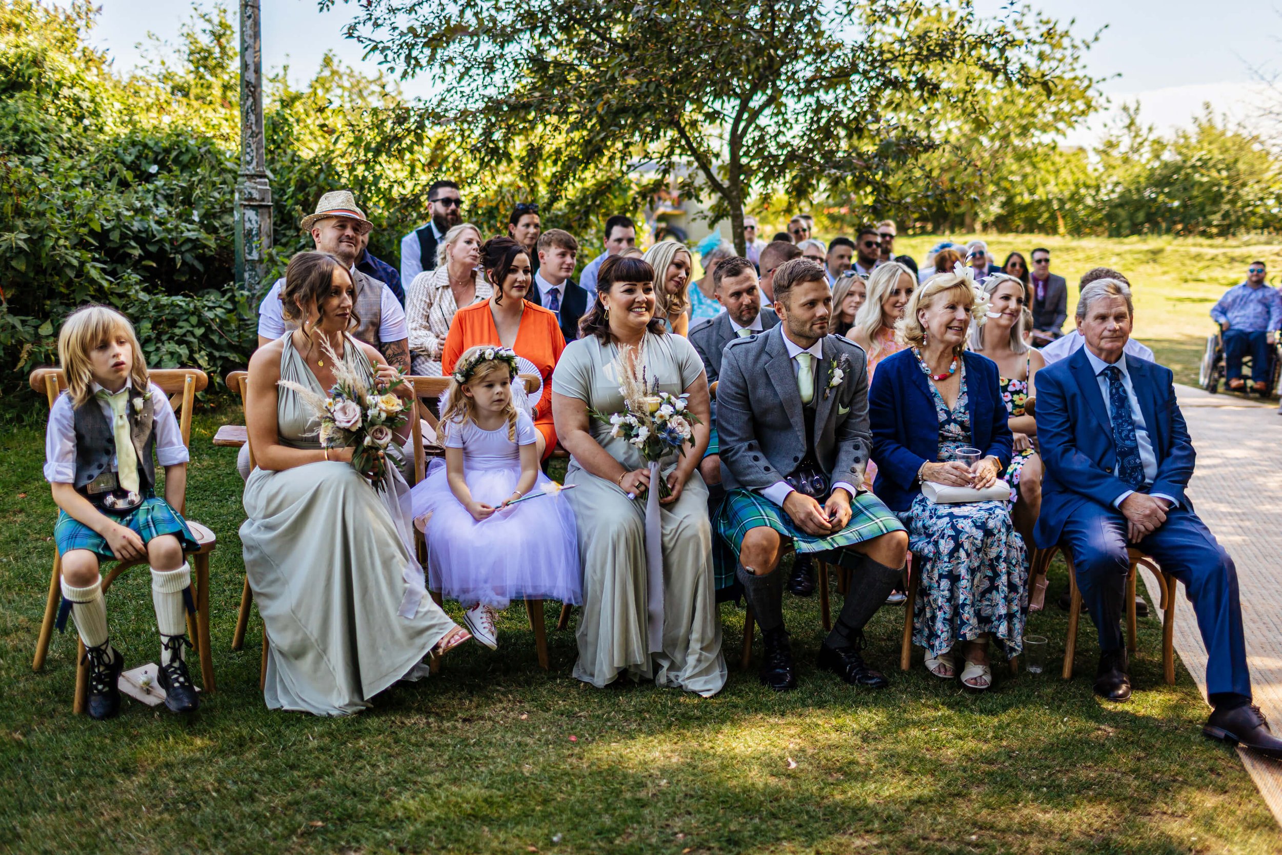 Wedding guests at an outdoor ceremony in the sunshine