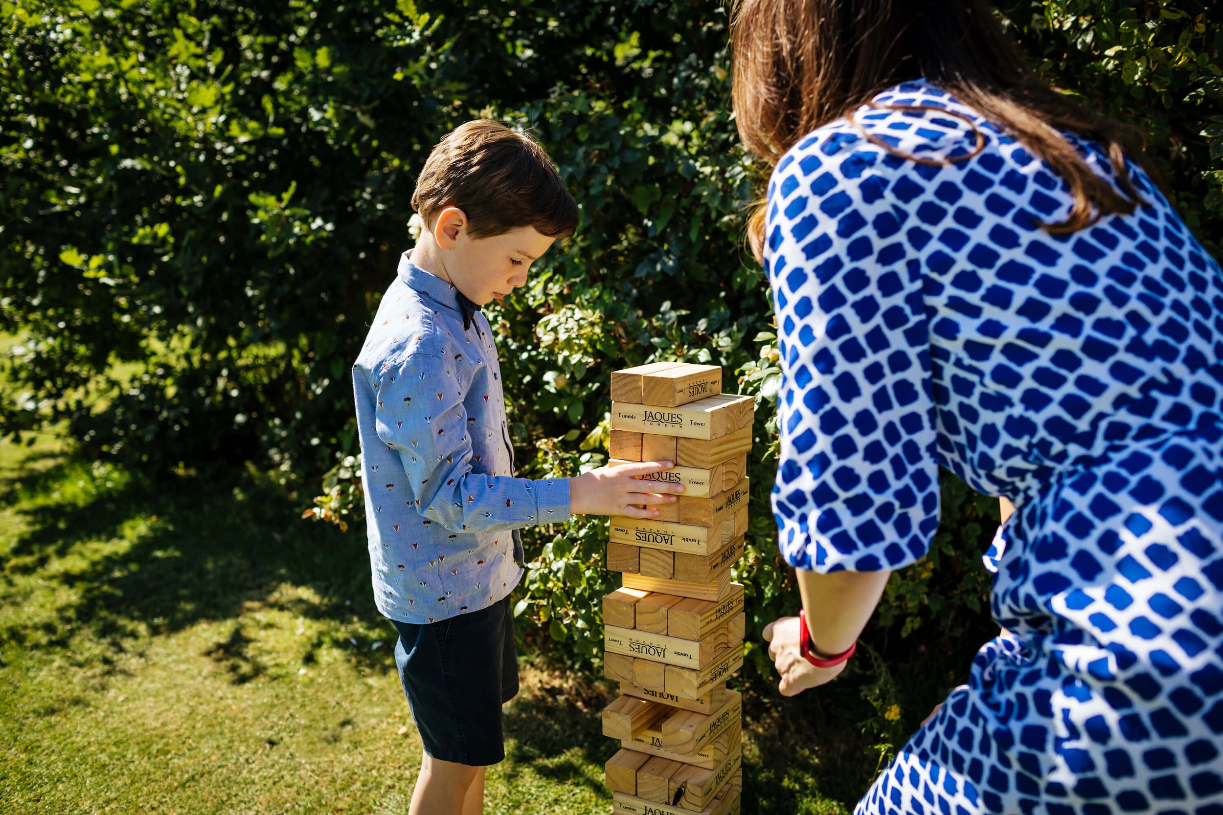 Young boy plays jenga at a sunny wedding in Yorkshire