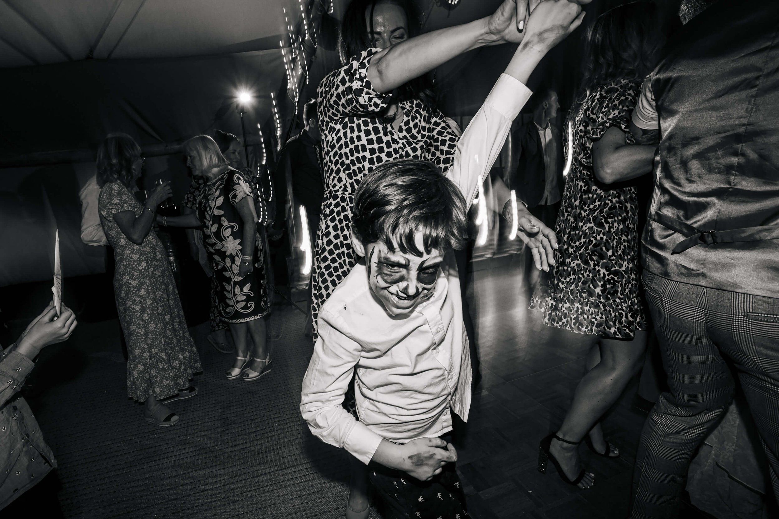 Young boy in face paint dancing at a wedding