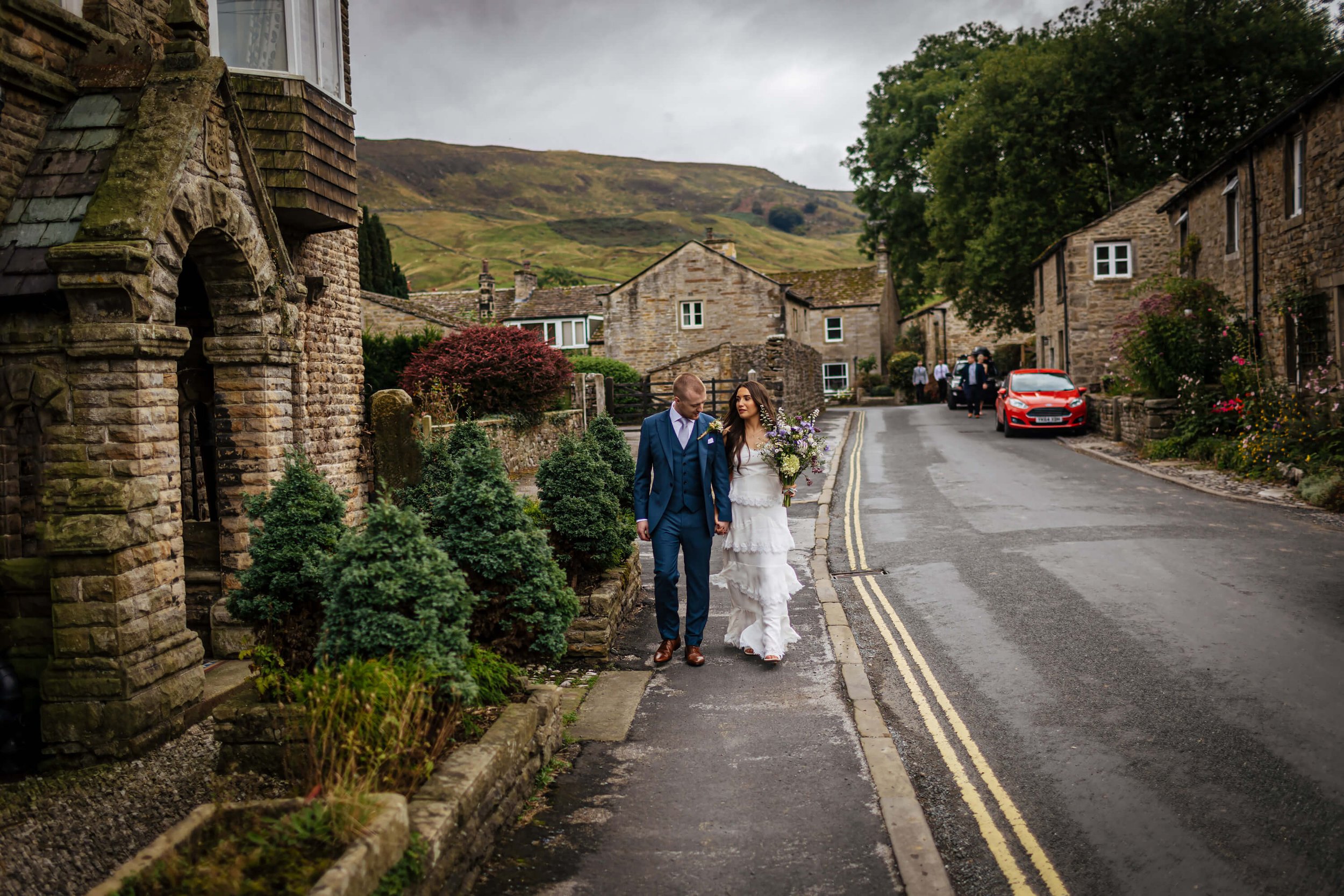 Bride and groom walking through Burnsall village to their wedding reception