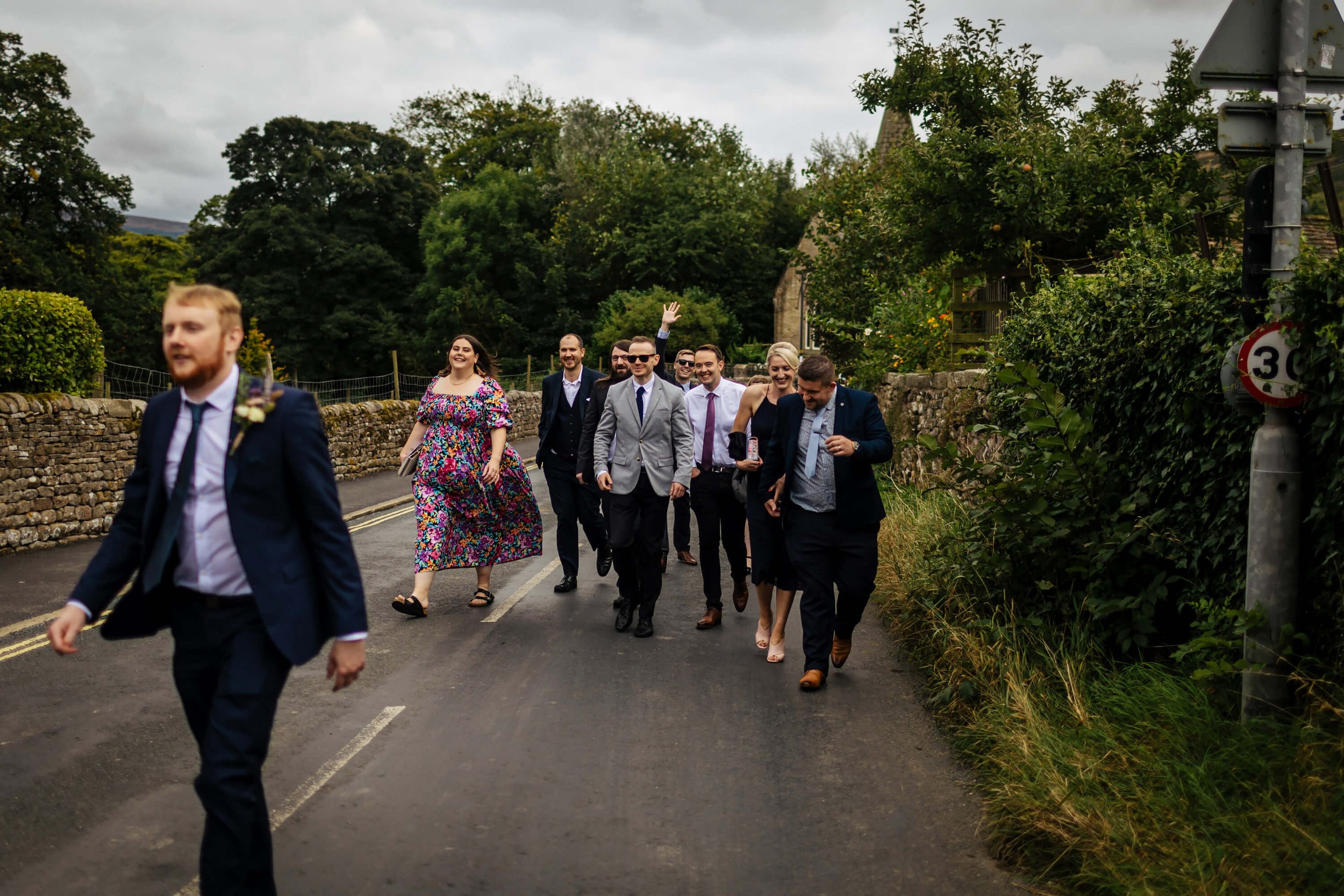 Wedding guests walking through Burnsall streets
