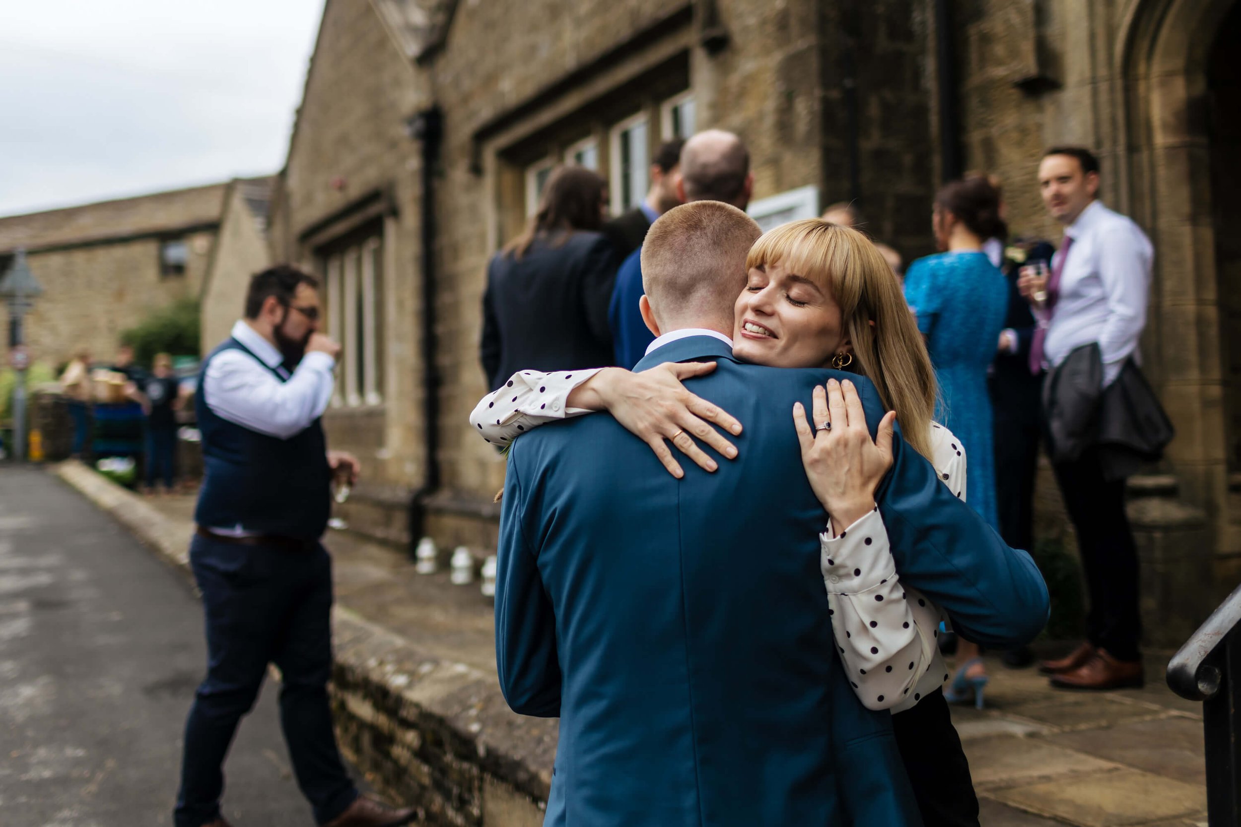 Groom and wedding guest hugging at Burnsall Village Hall