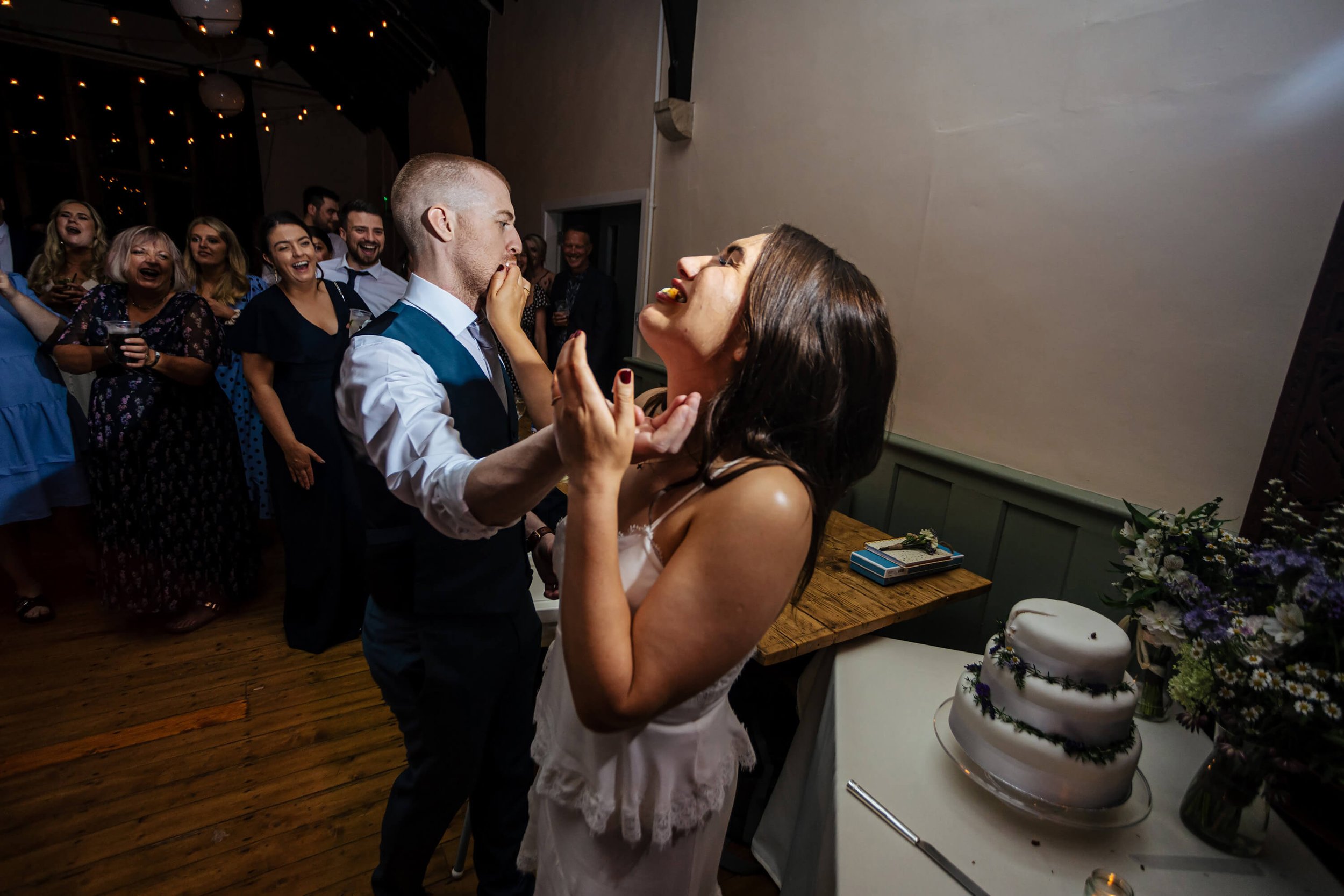 Bride and groom stuffing wedding cake into each others mouths