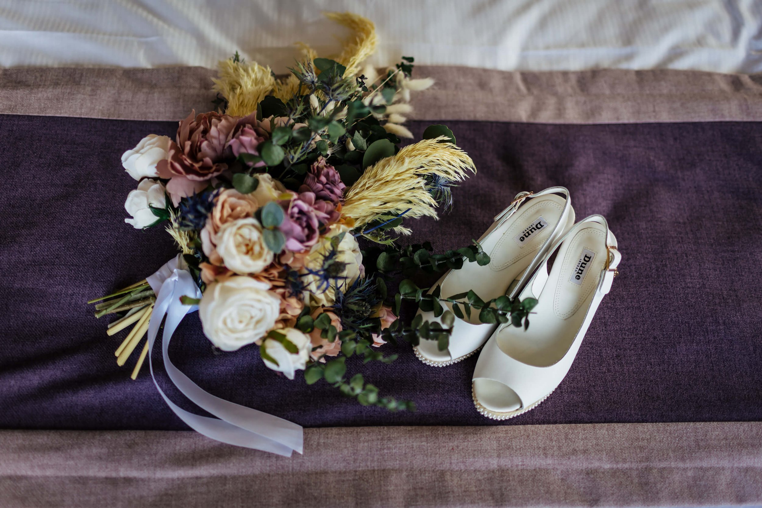 Wedding bouquet and shoes placed on the bed