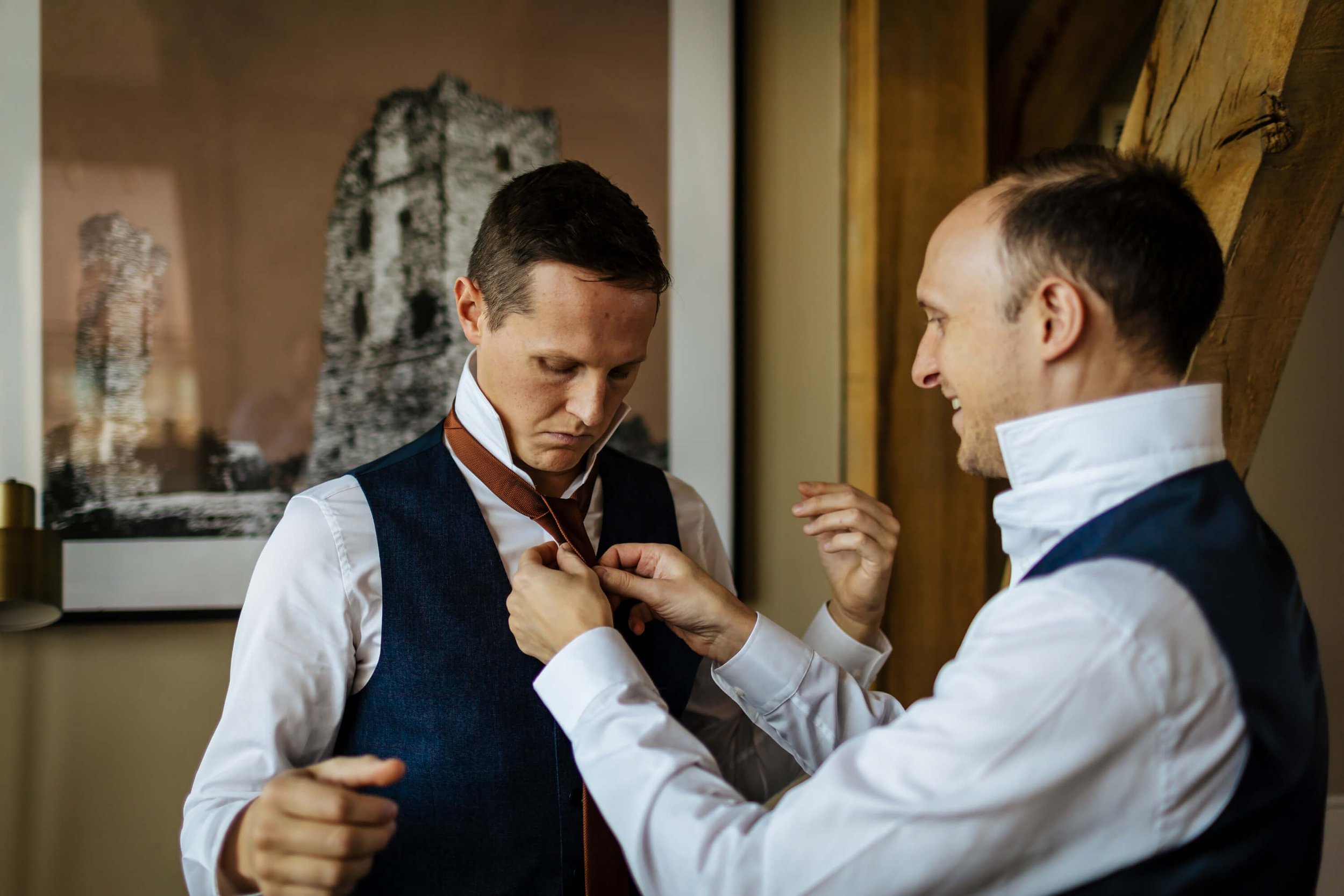Groom having his tie put on for the wedding ceremony