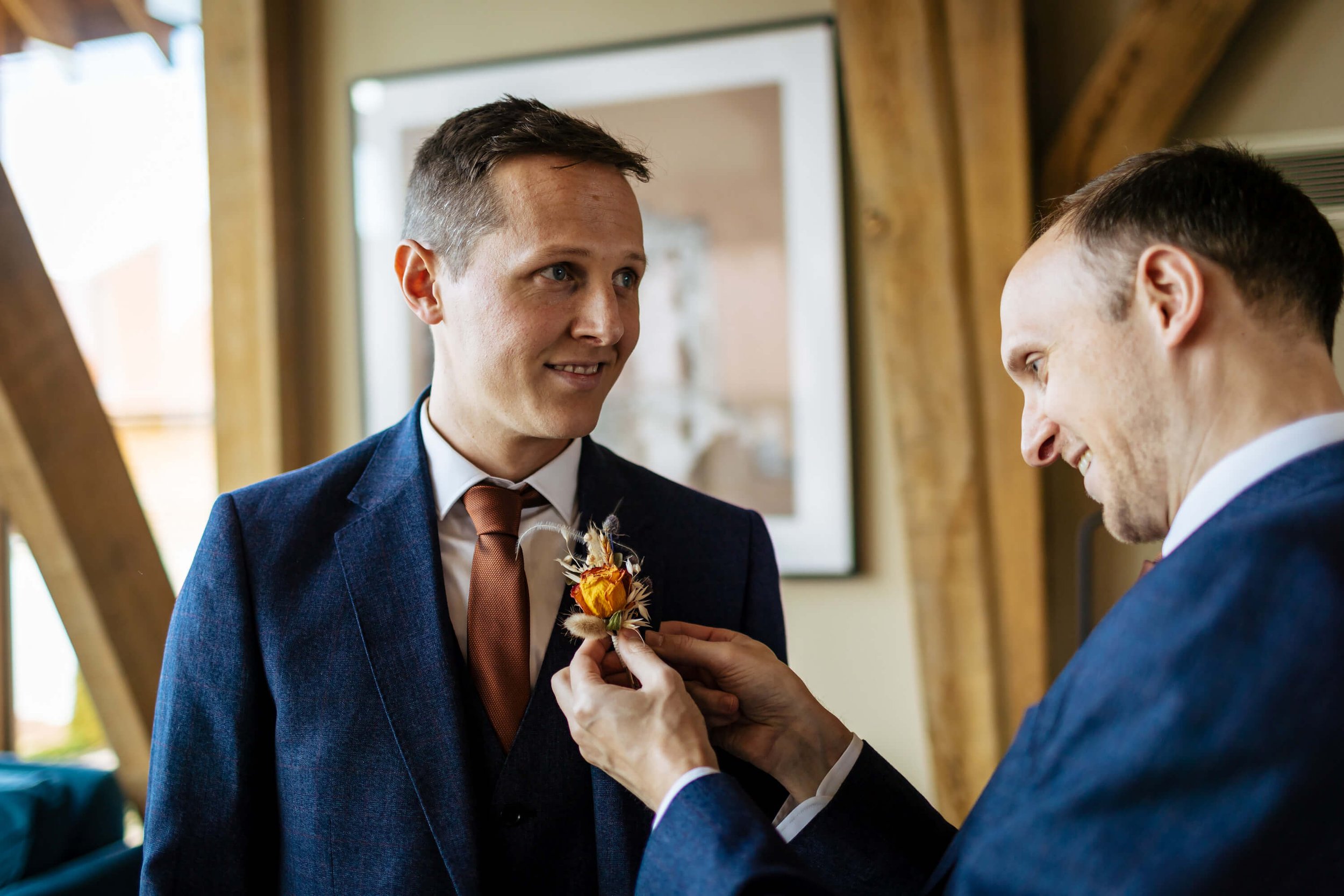 Best man helps the groom with his buttonhole on his suit