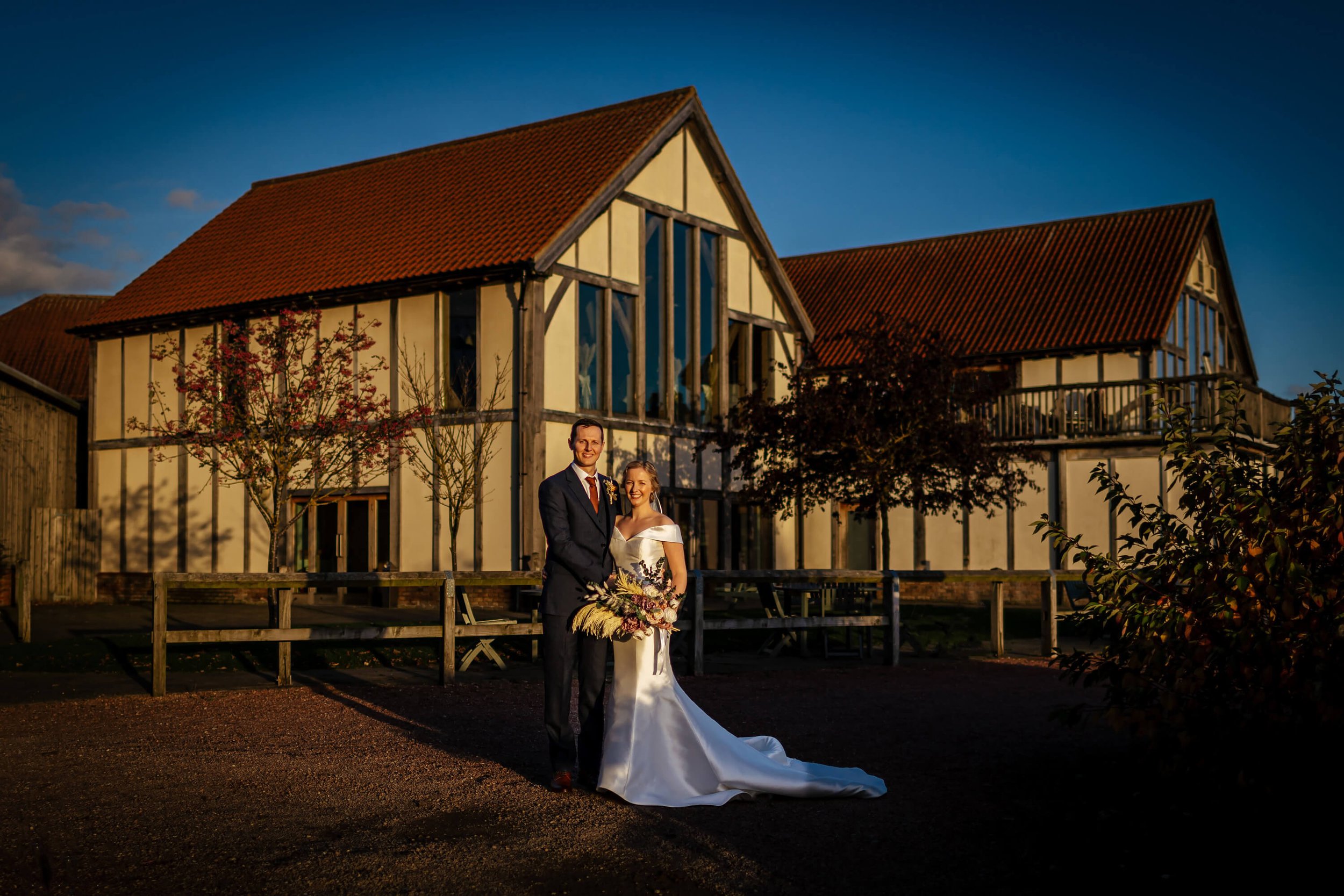 Bride and groom pose in front of Sandburn Hall for a photo