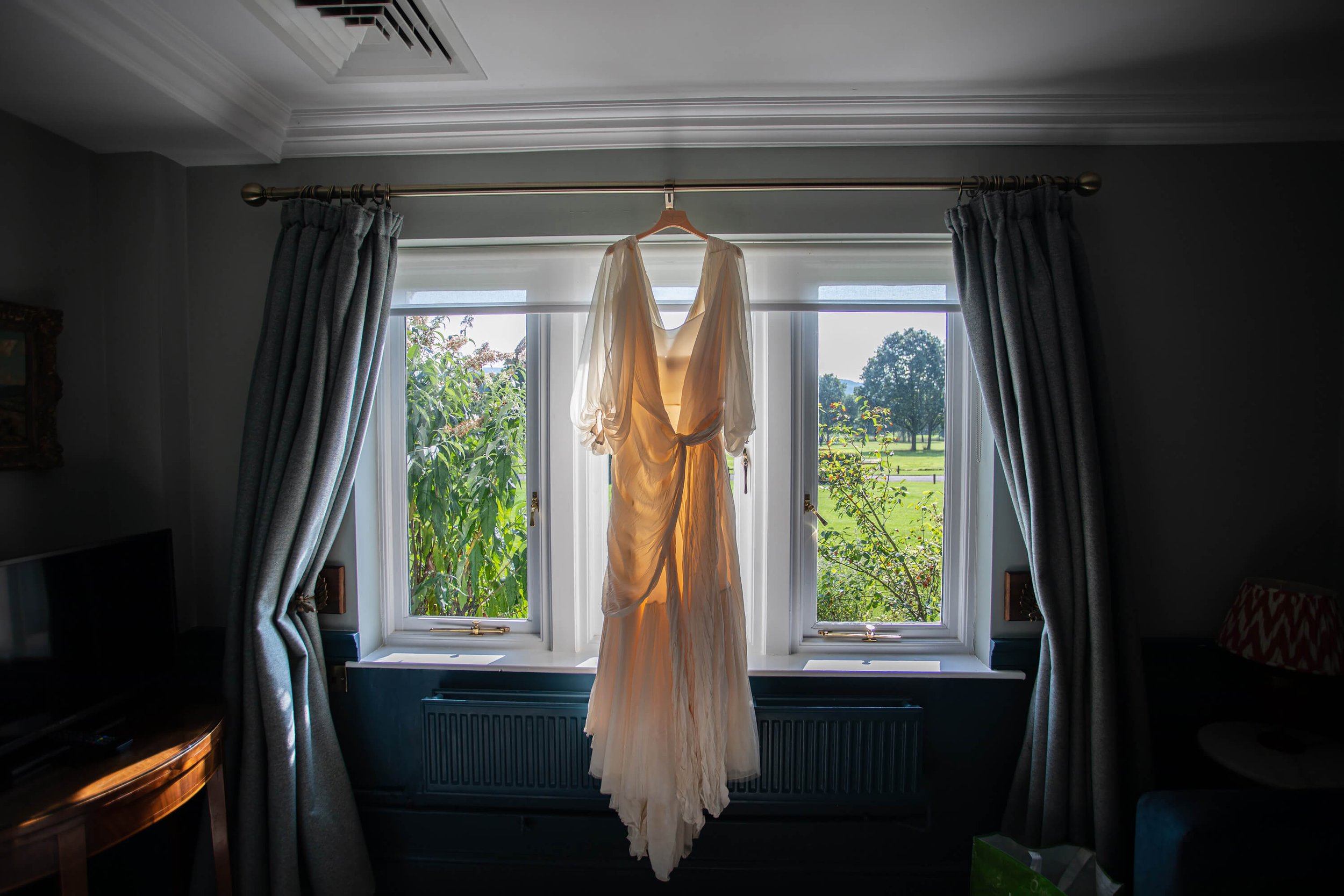 Wedding dress hanging up in the window sunshine
