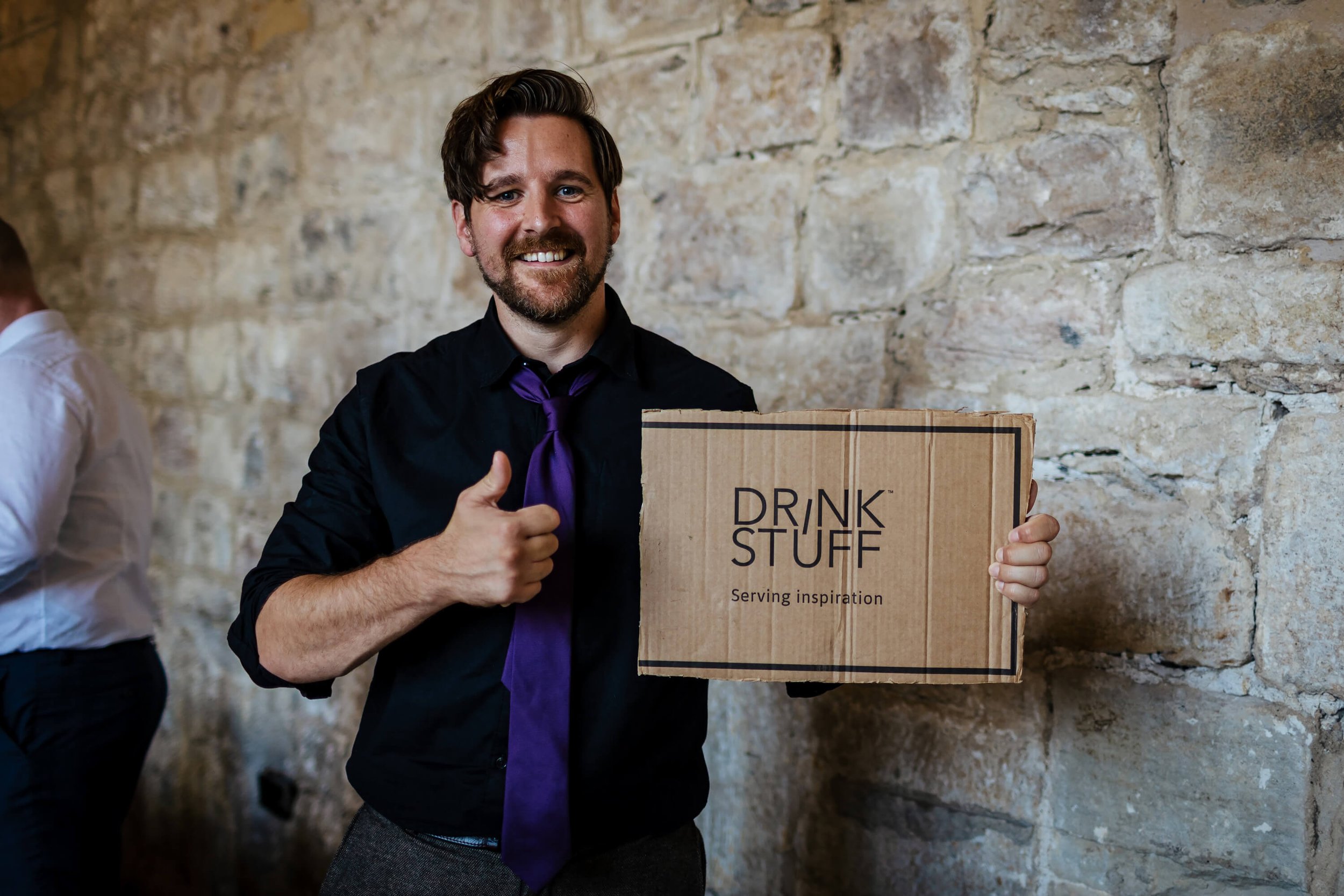 Man holding a funny sign at a wedding that says drink stuff