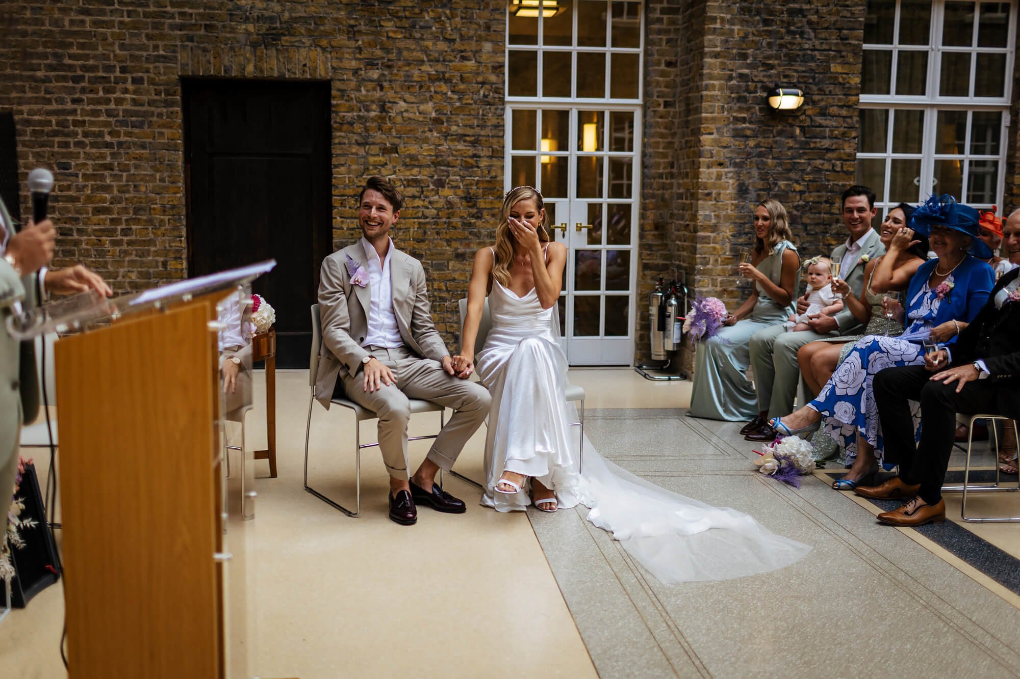 The bride and groom laughing during a reading at their wedding service