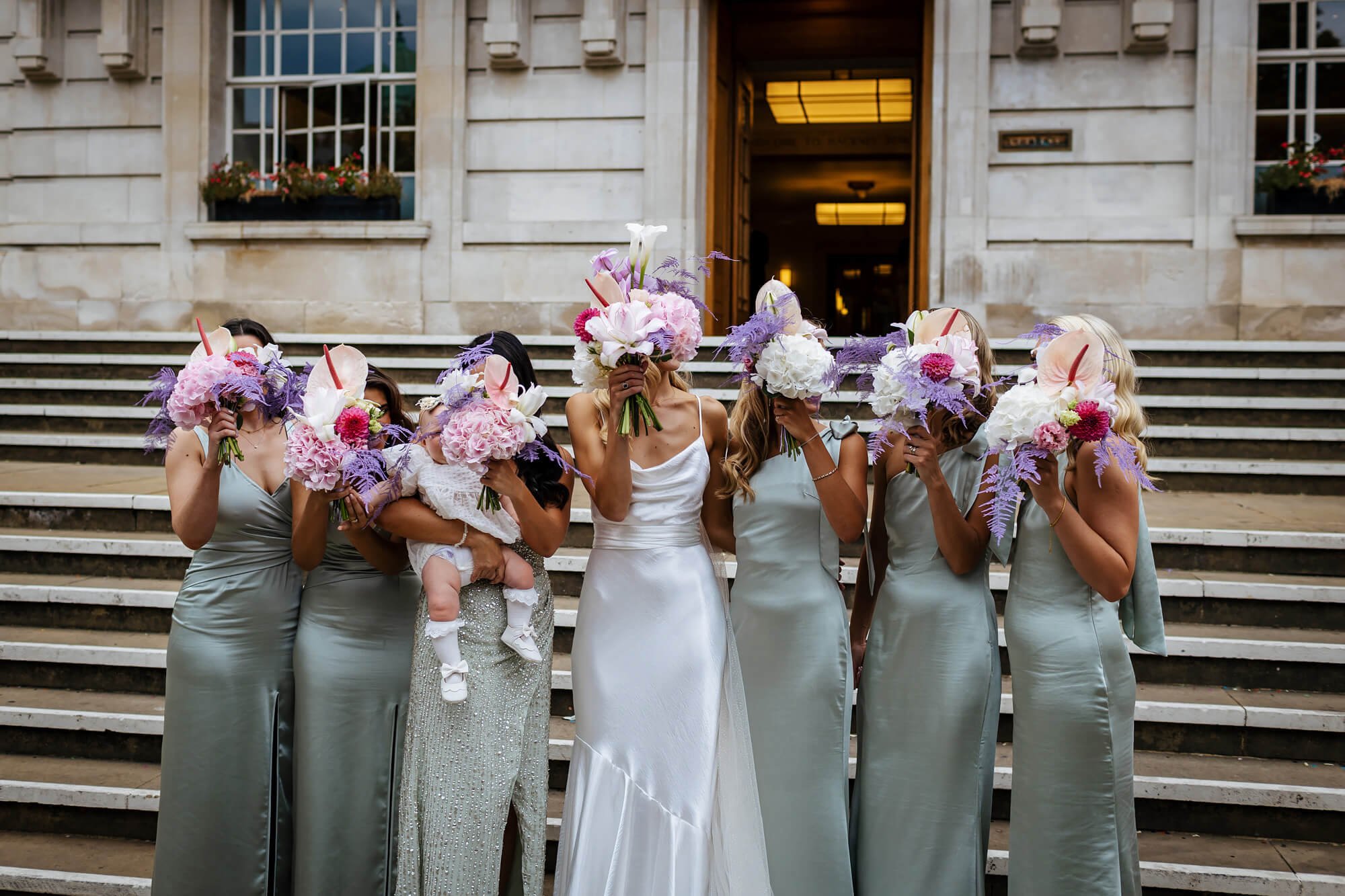 Bride and bridesmaids with their flowers in front of their faces
