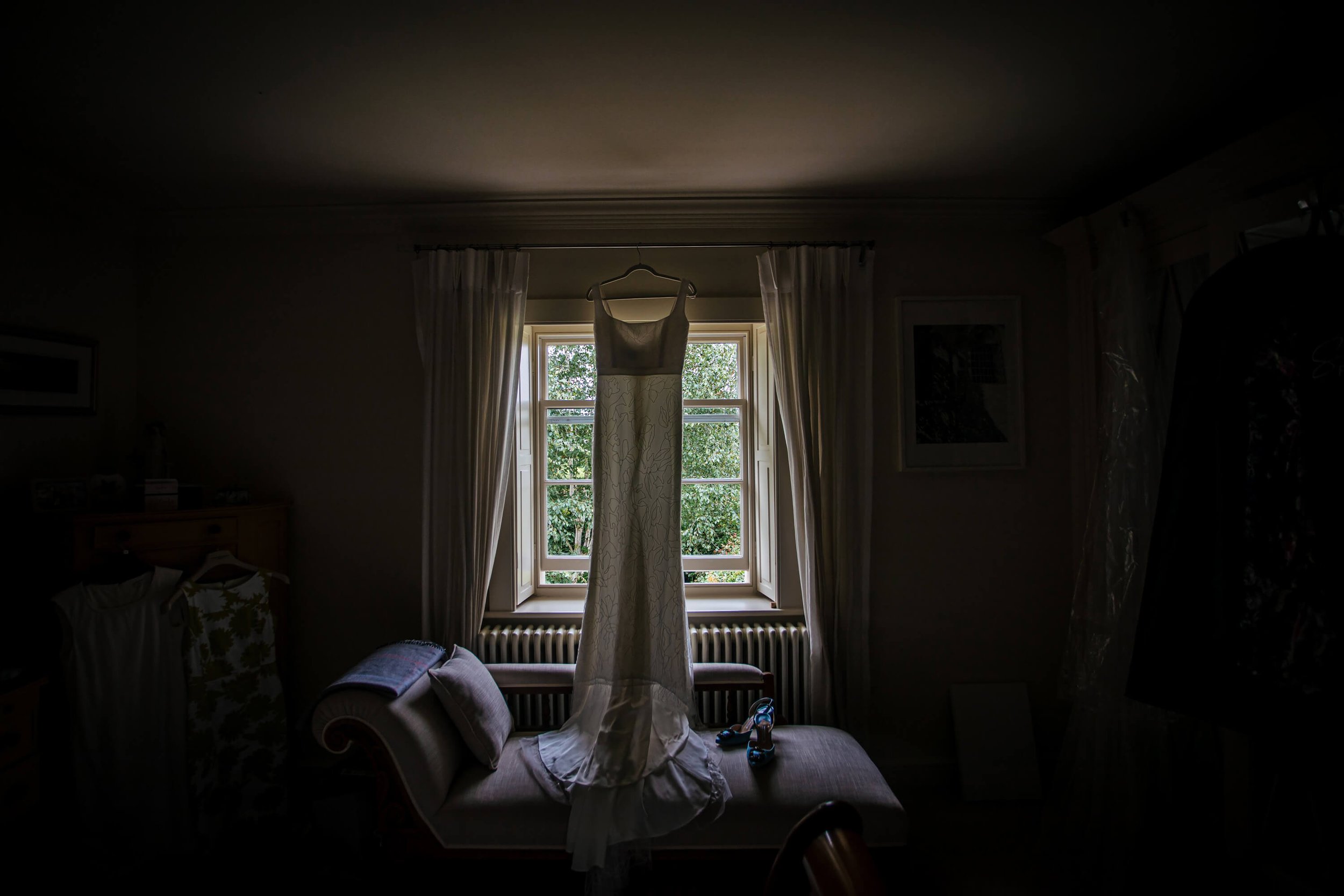 Wedding dress hanging in the window light