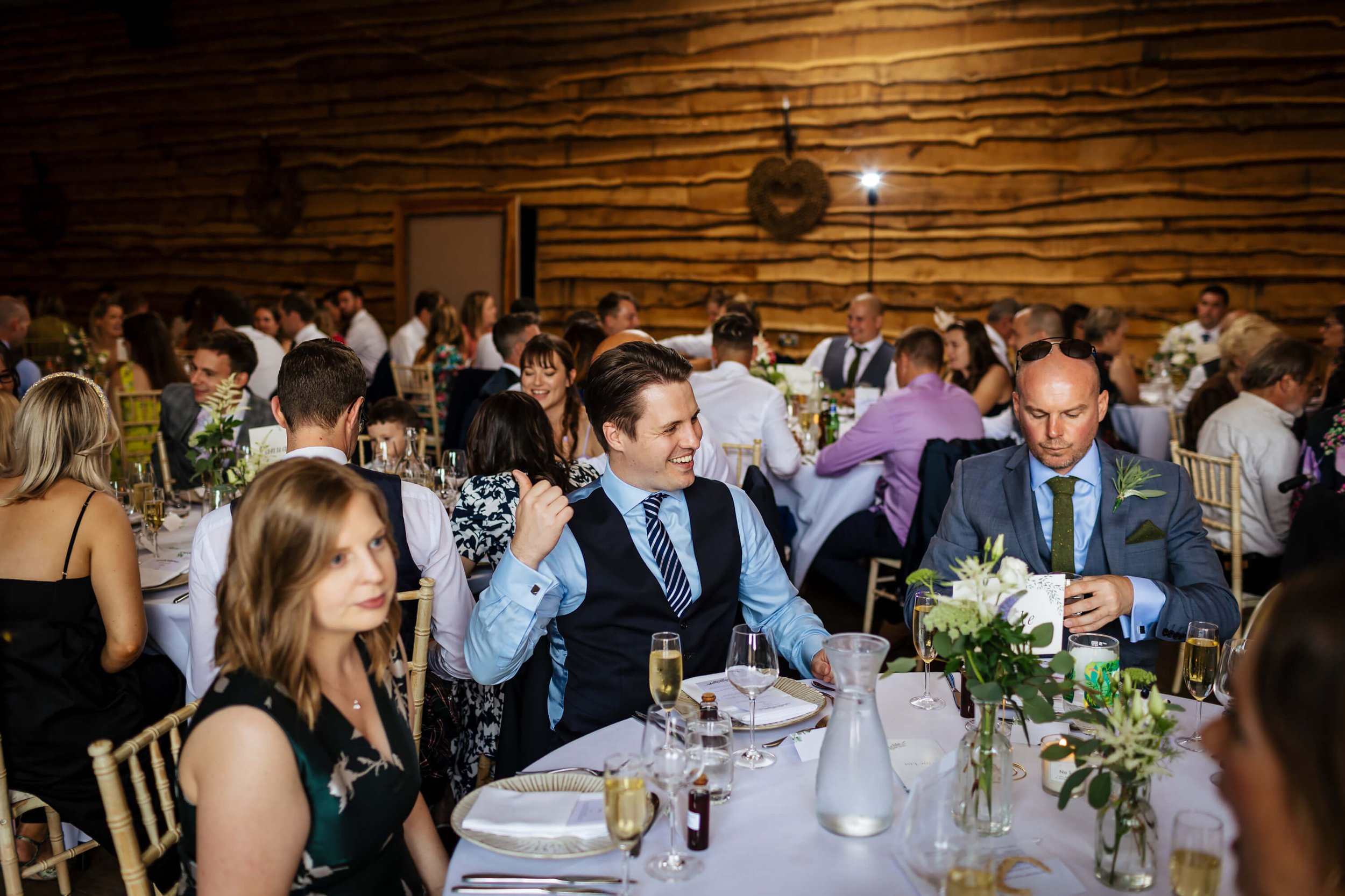 Wedding guests laughing as they wait for the speeches