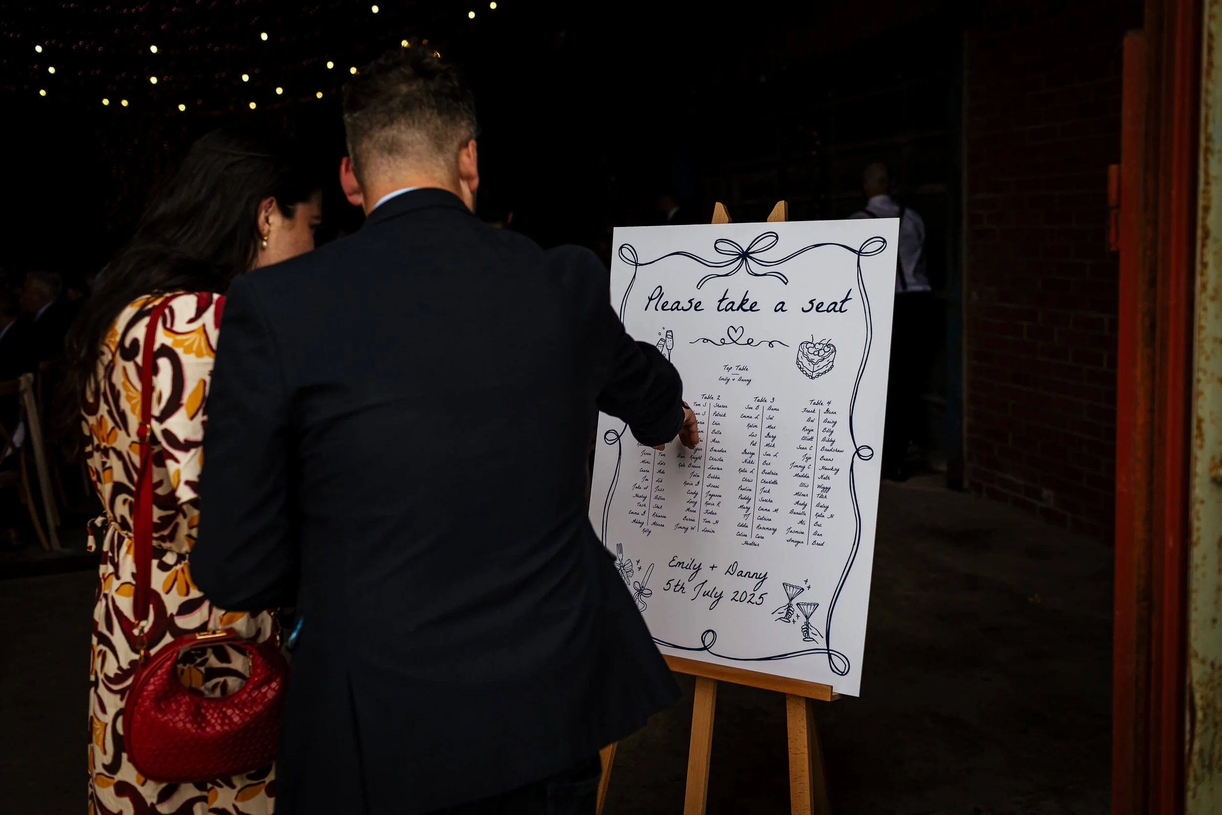 Wedding guests pointing at the seating plan for food