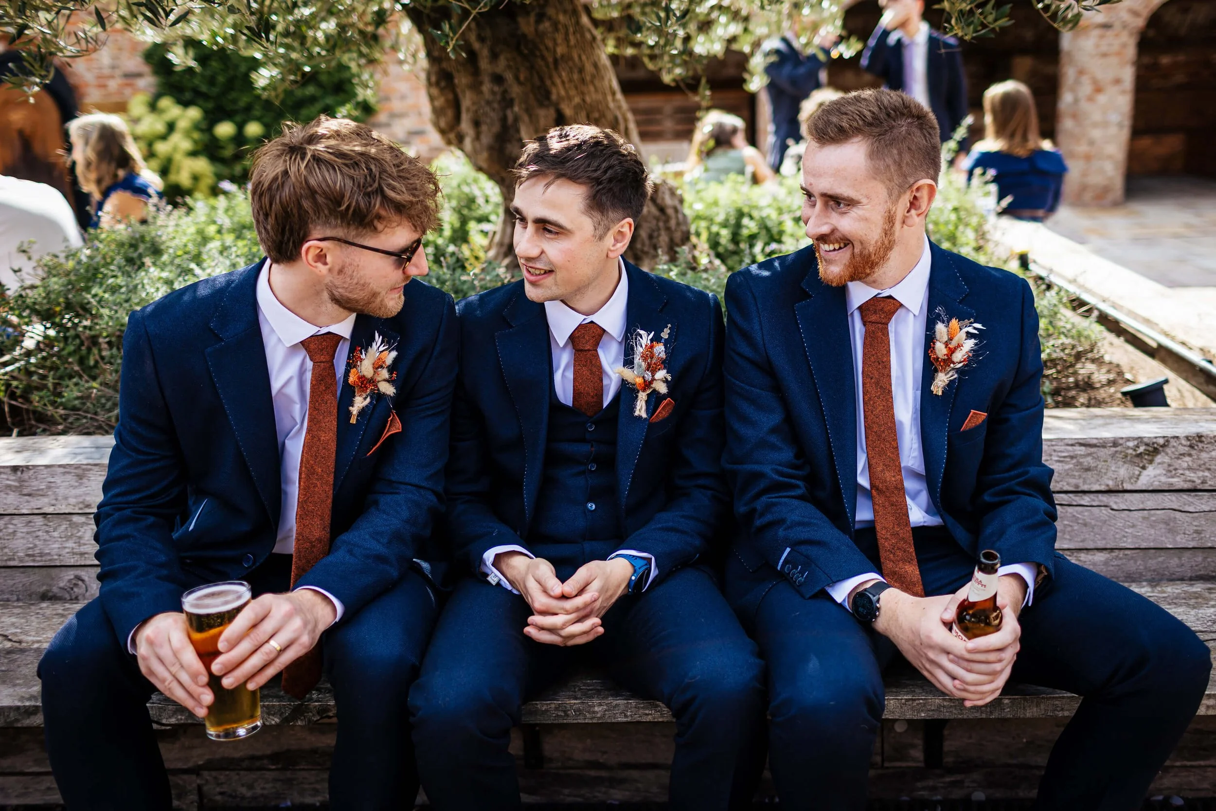 Groom sitting and talking to two of his groomsmen on the wedding day