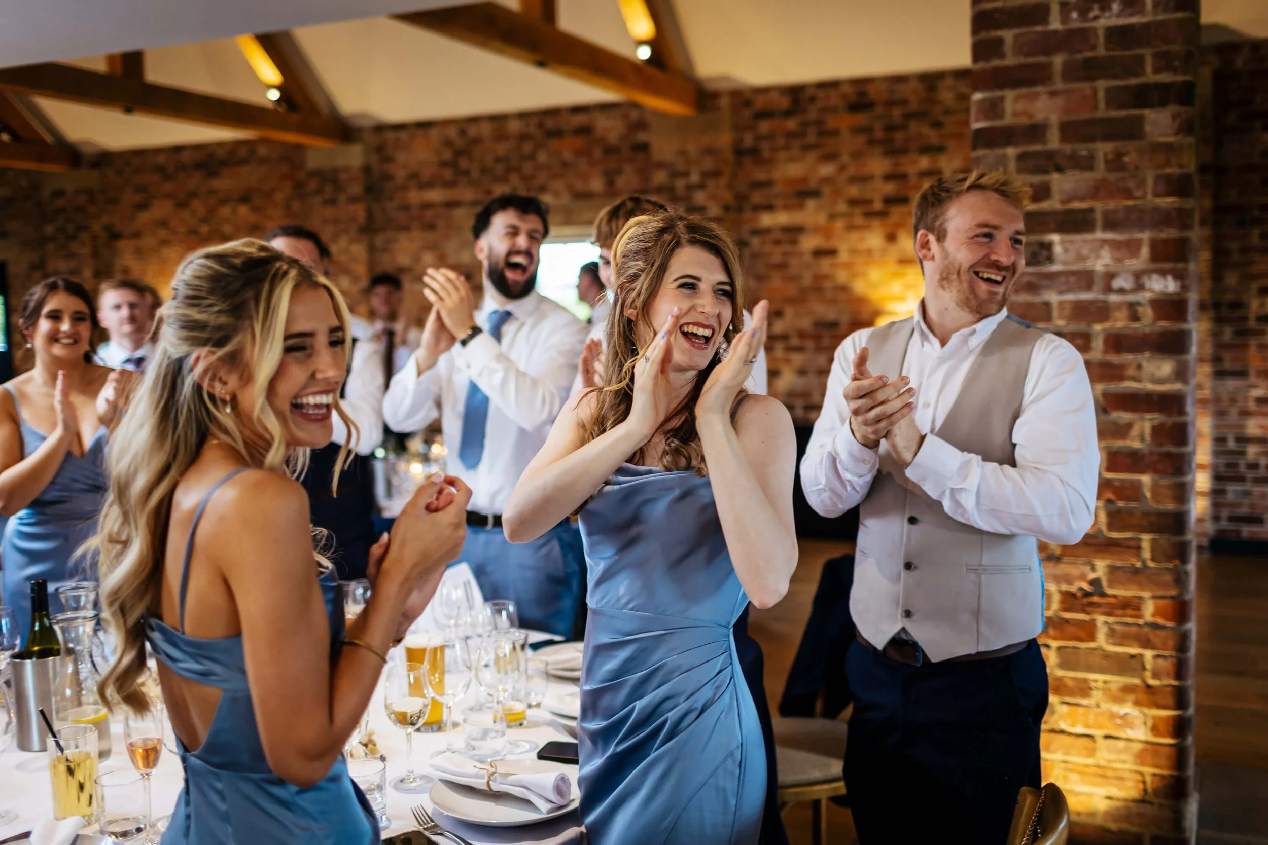 Wedding guests cheering as the newlyweds enter the room