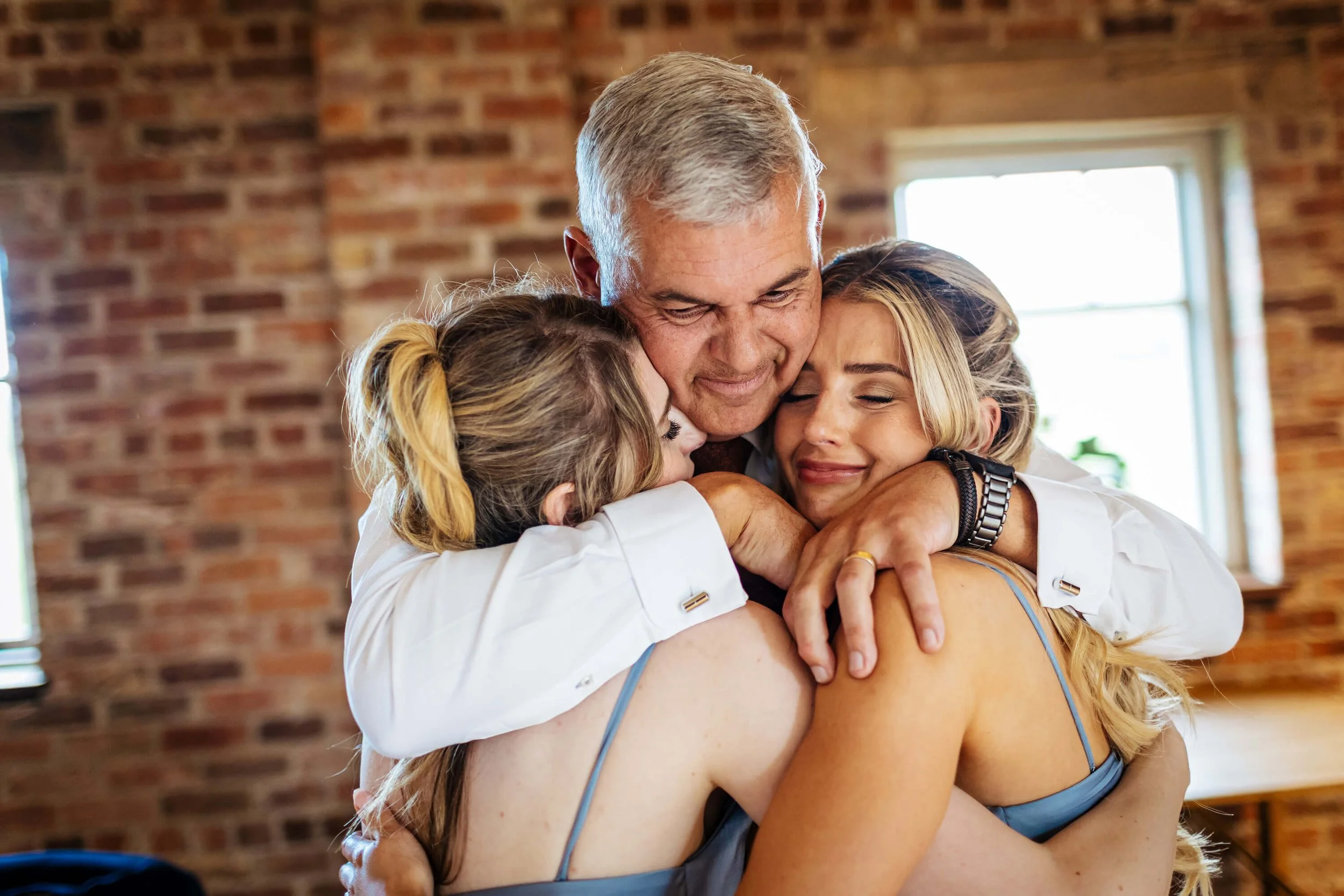 Dad and bridesmaids hugging during the wedding speeches