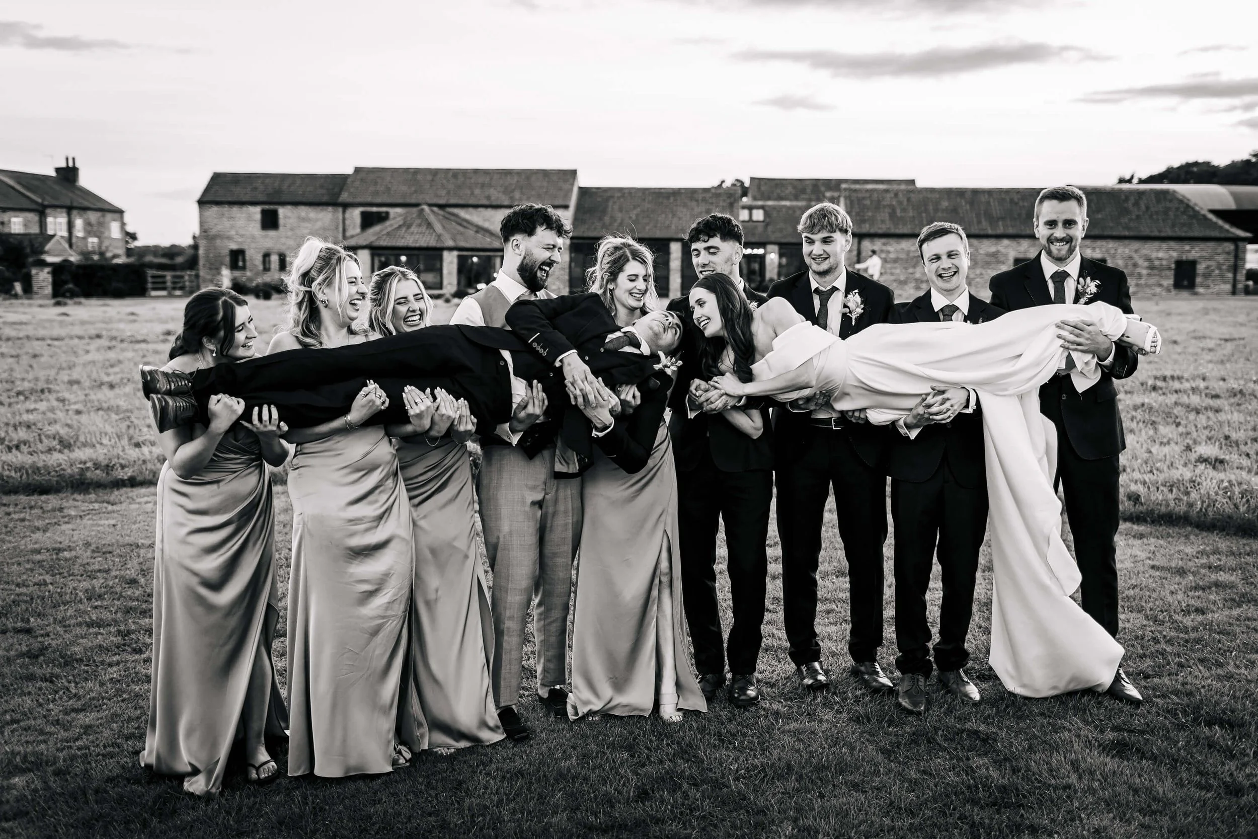 Wedding party holding up the bride and groom for a photo