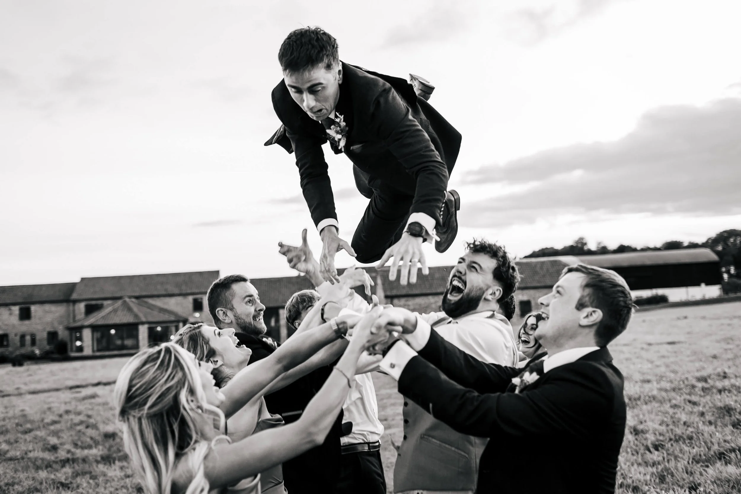 Guests throw the groom in the air on his wedding day