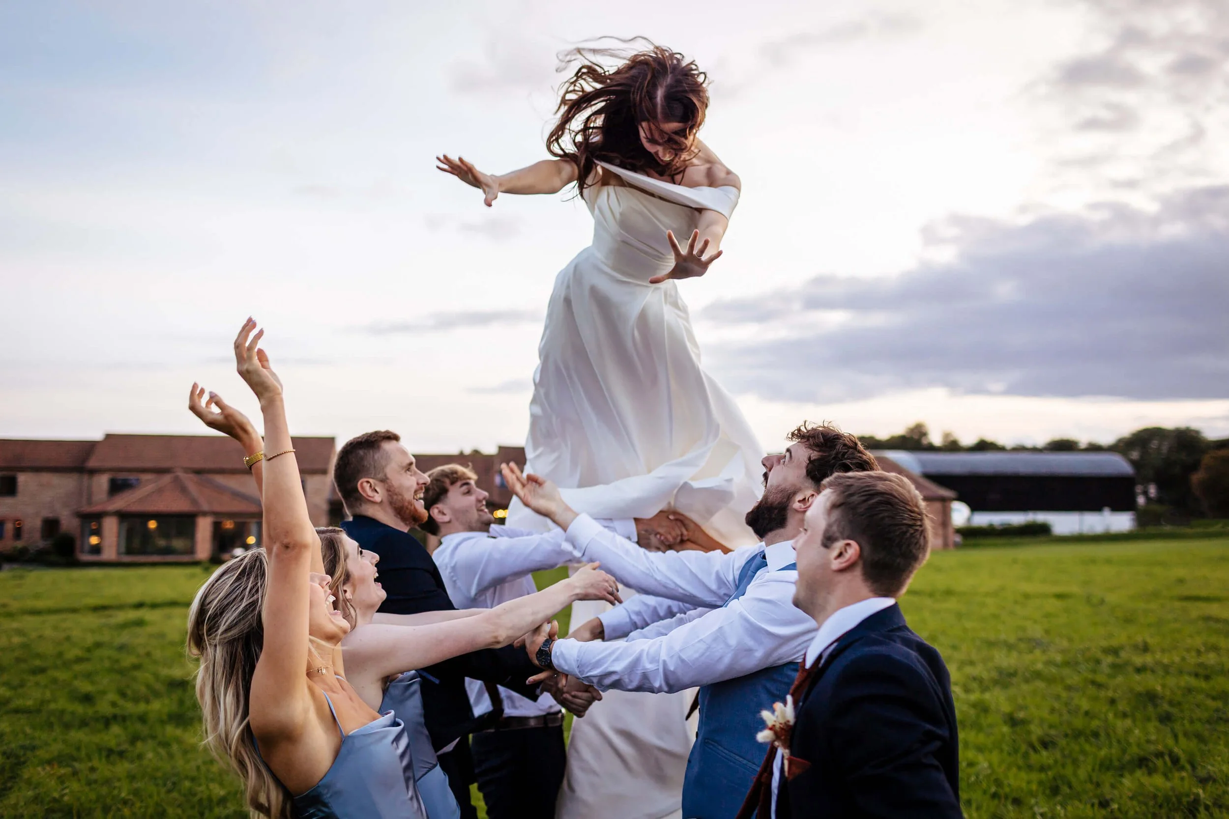 Guests throw the bride in the air on her wedding day