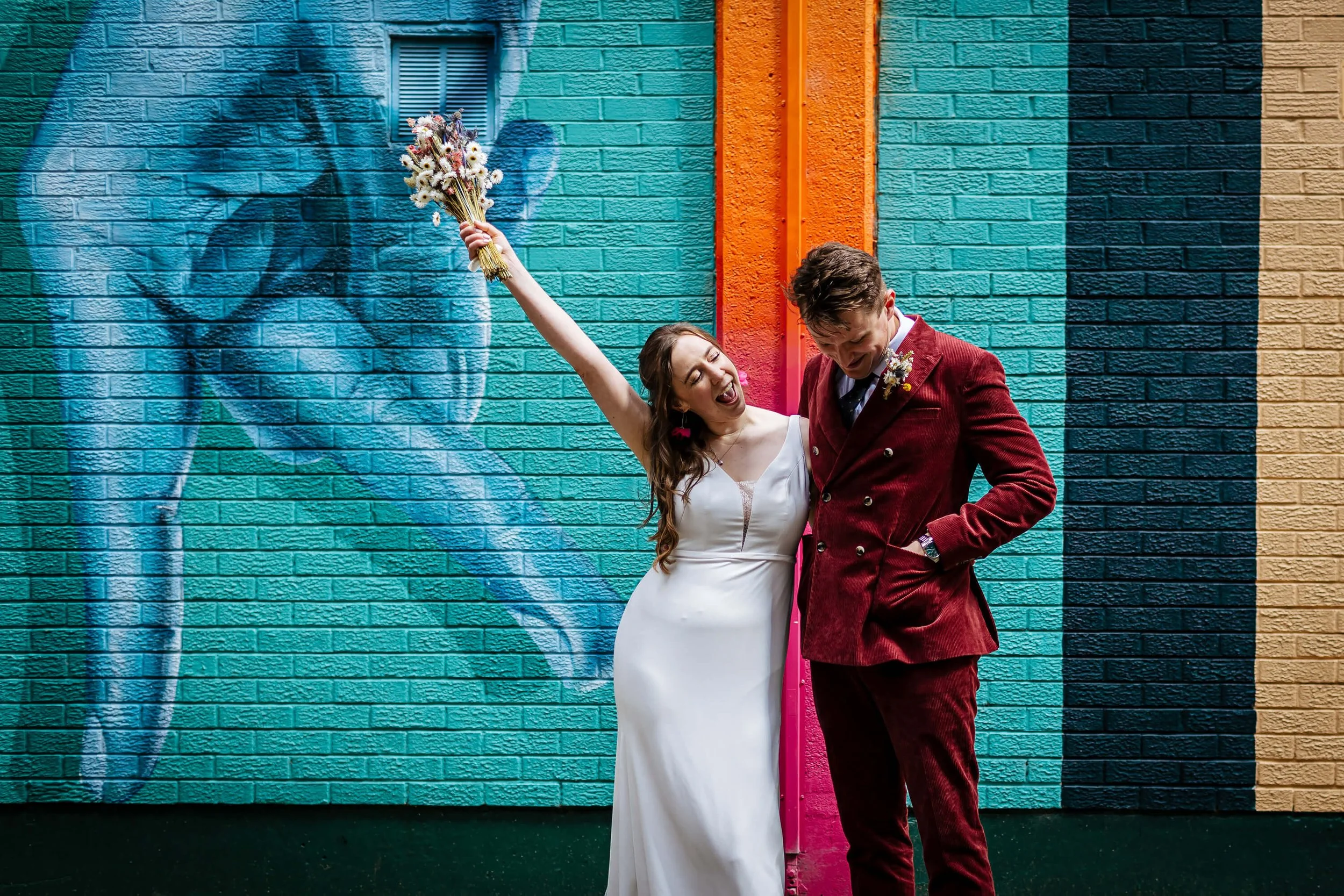 Bride and groom in front of a colourful mural in Leeds