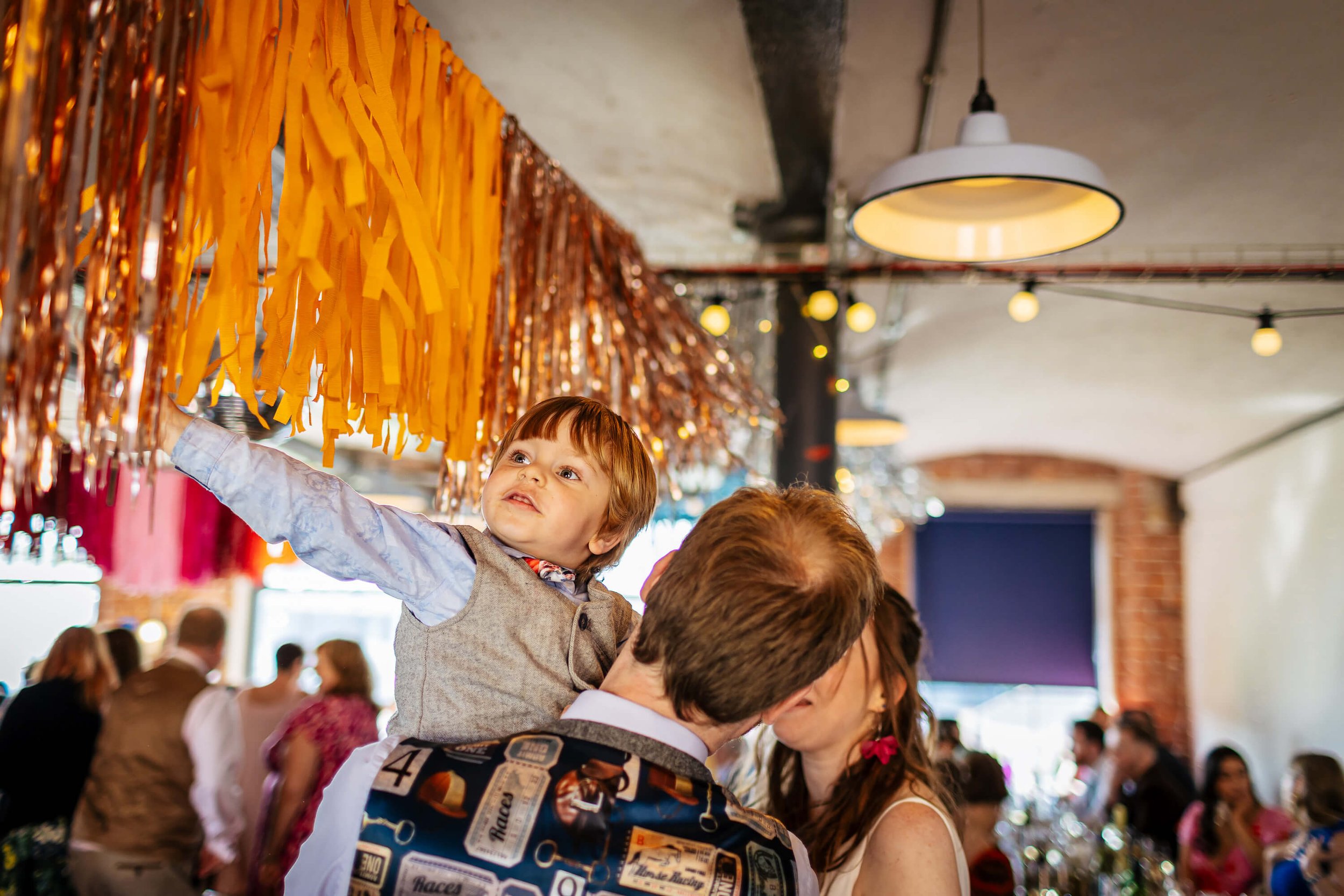 A young boy playing with the wedding bunting at Northern Monk Refectory