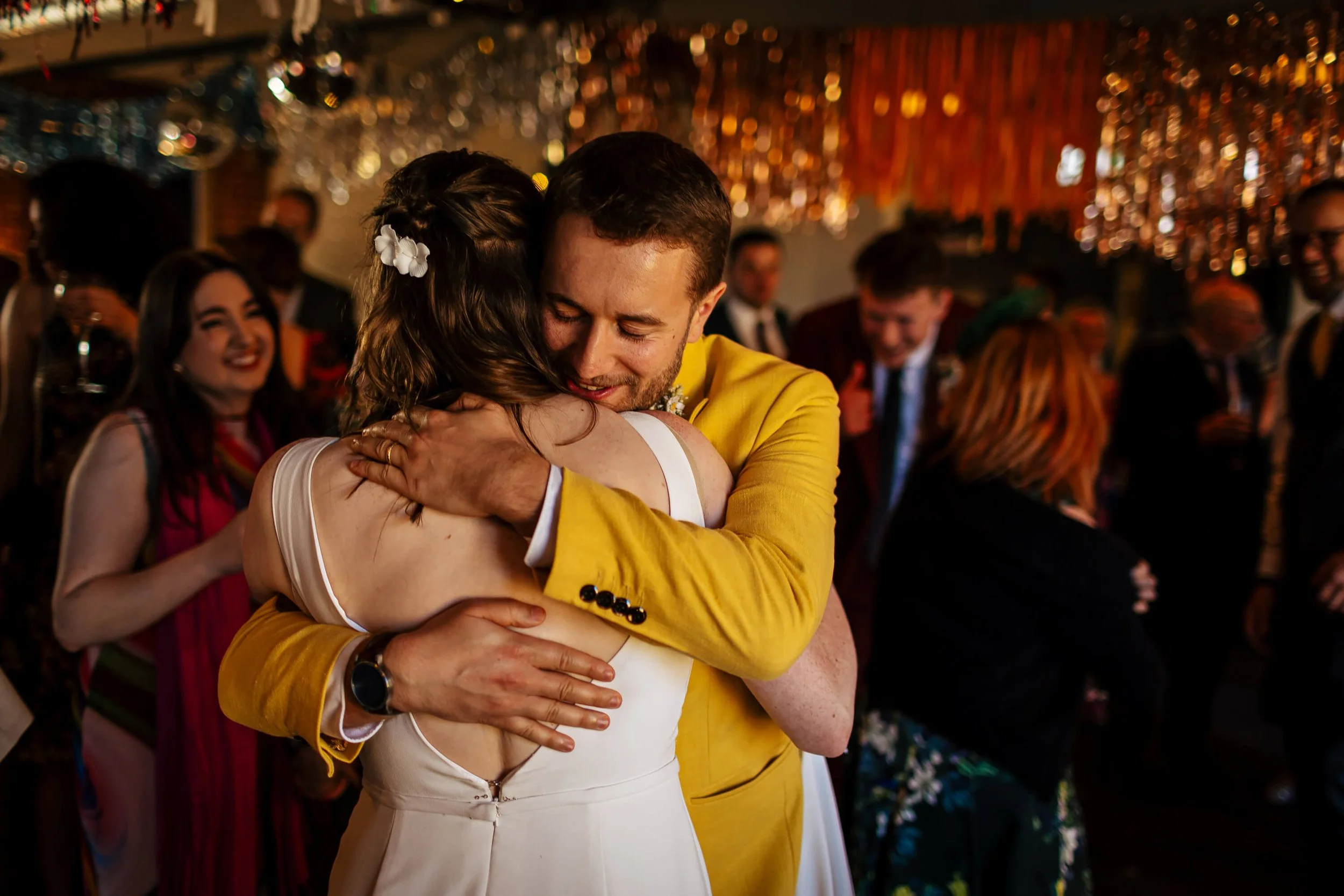 Wedding guest hugs the bride on the dance floor at her wedding