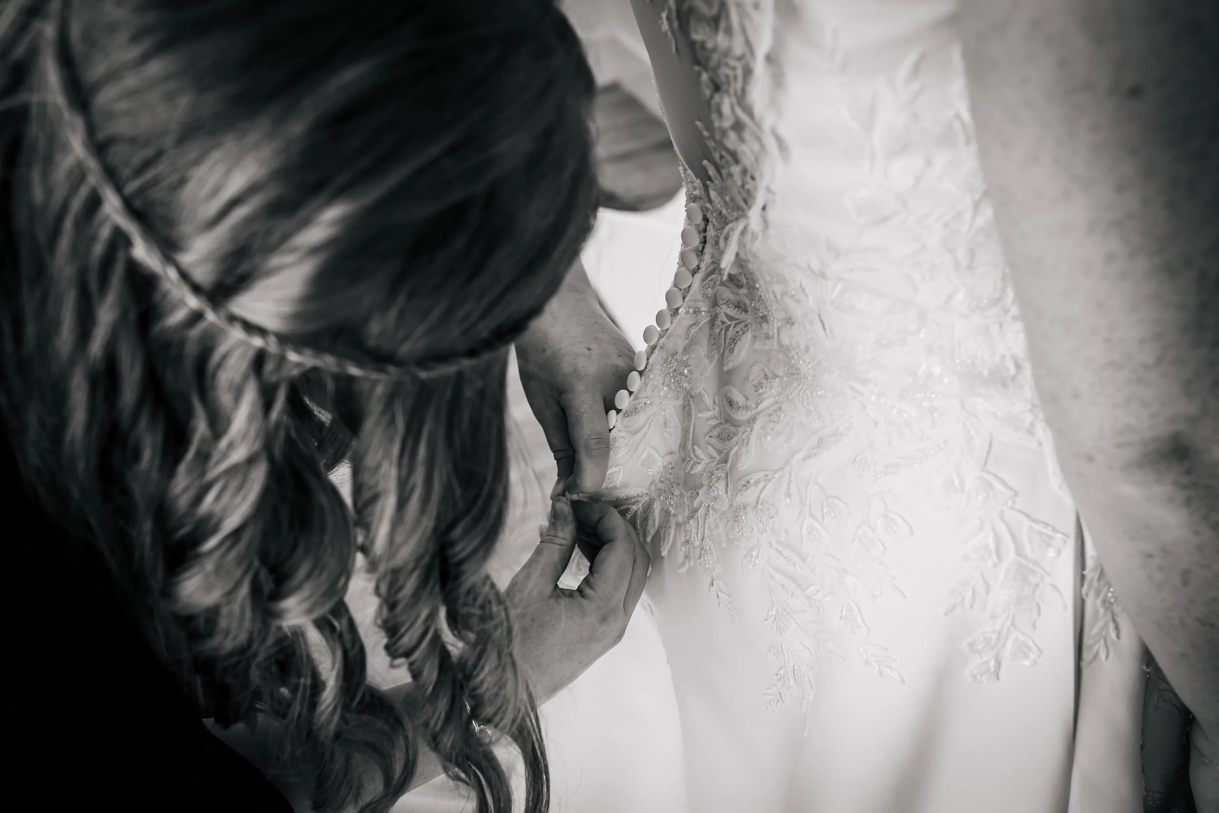 Bride having her dress fastened on her wedding morning