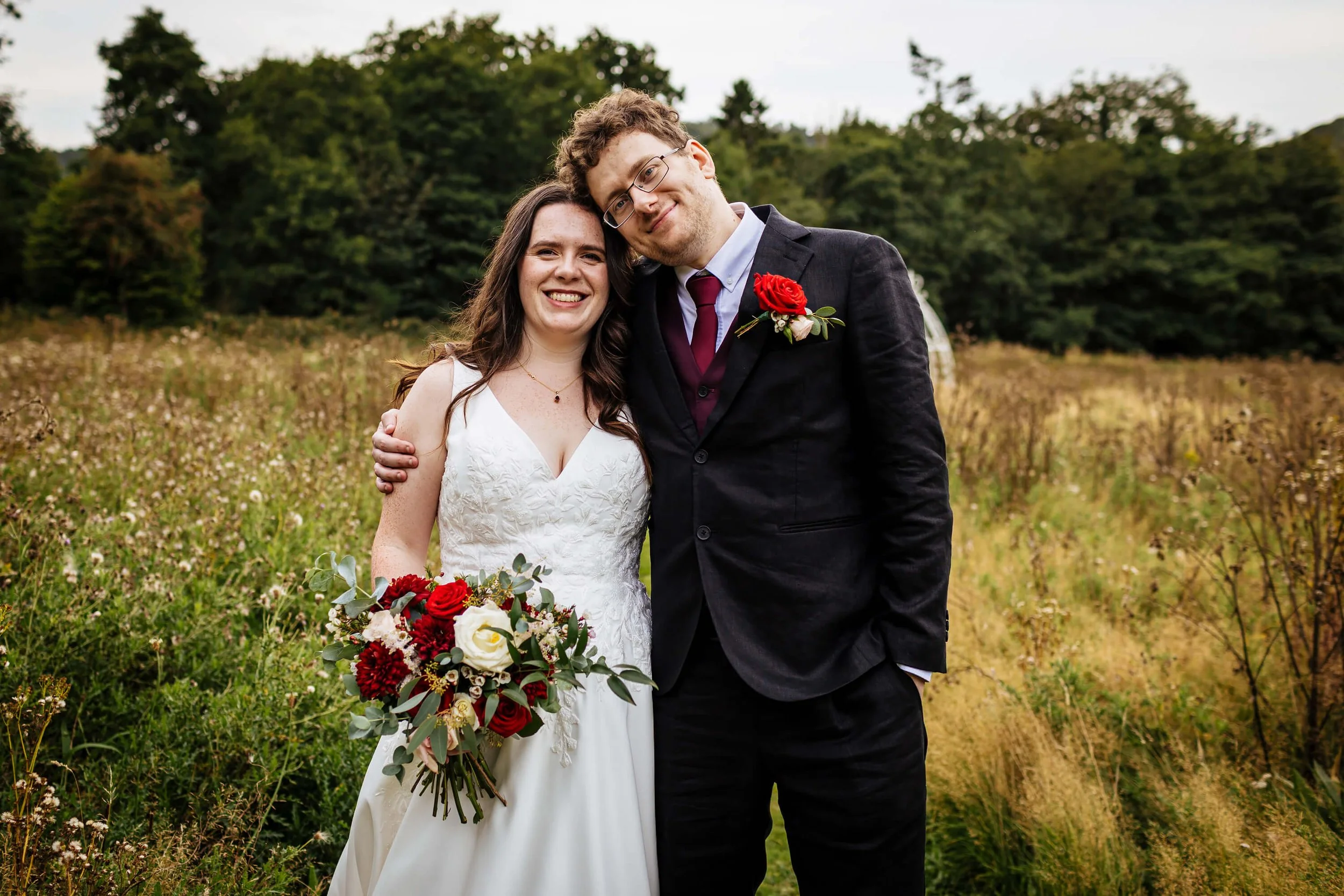 Bride and groom cheesy portrait in the field at their wedding