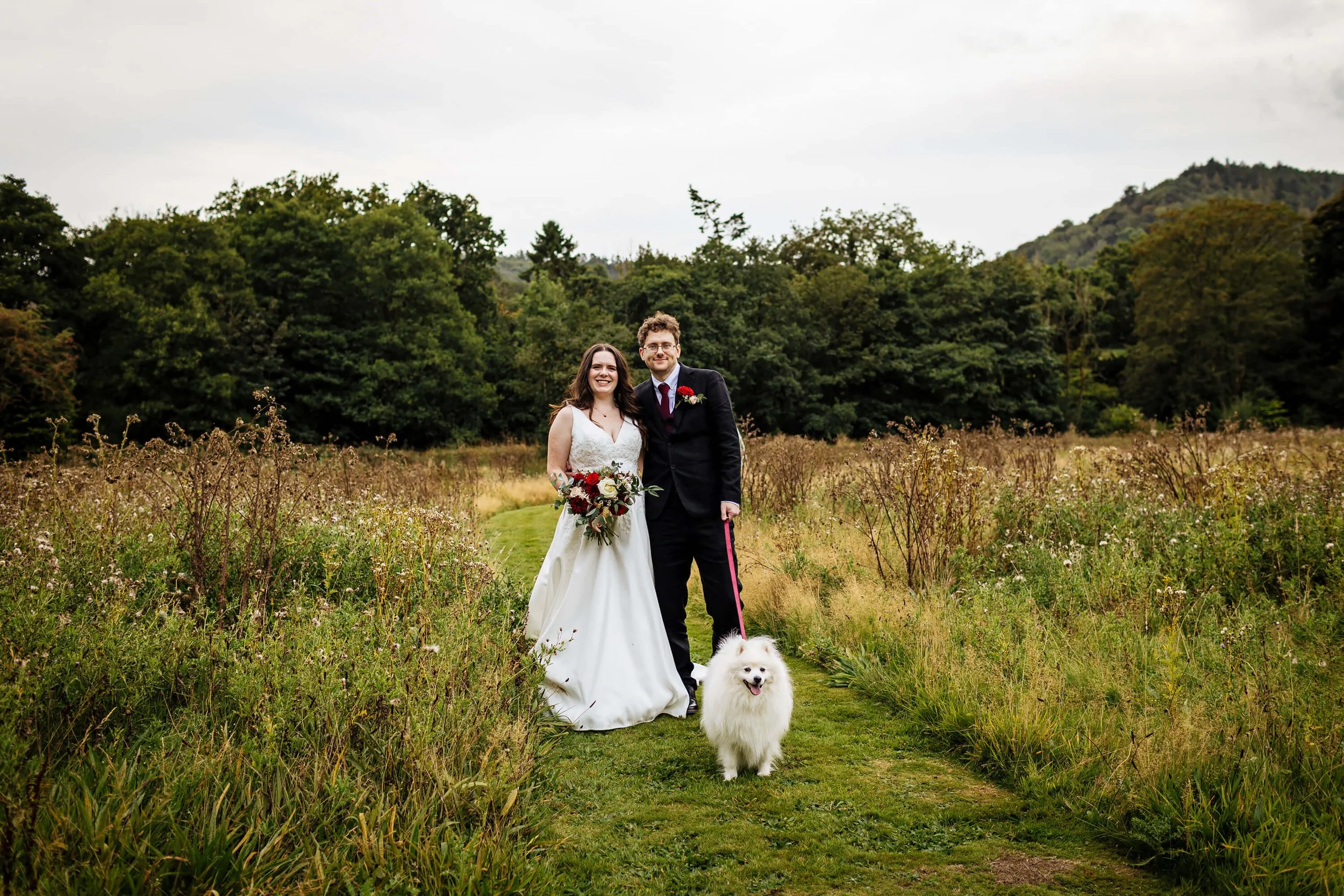 Bride and groom pose for a photo with their pet dog