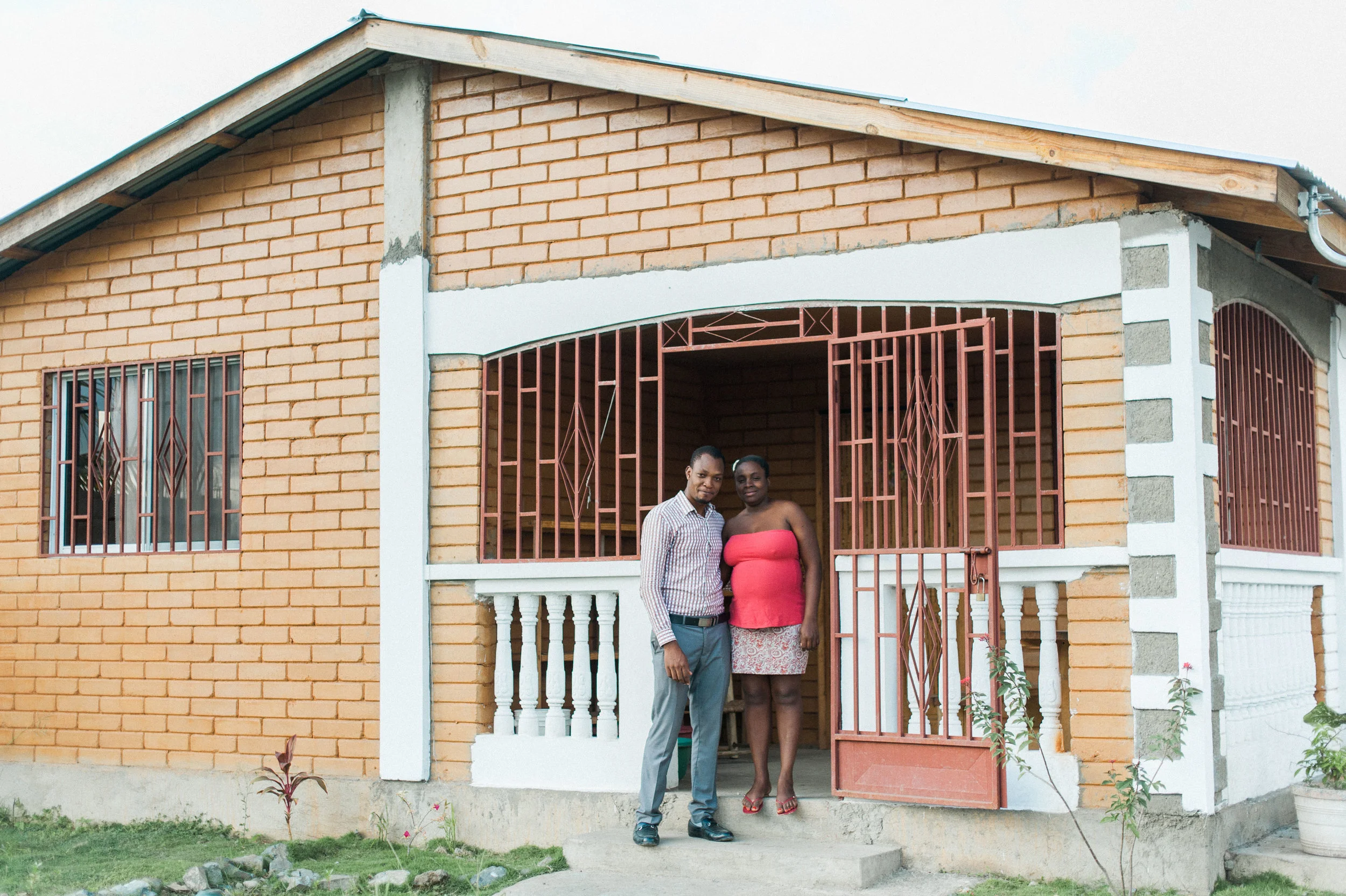 Manuacha and her husband on the front porch of their new earth block home.