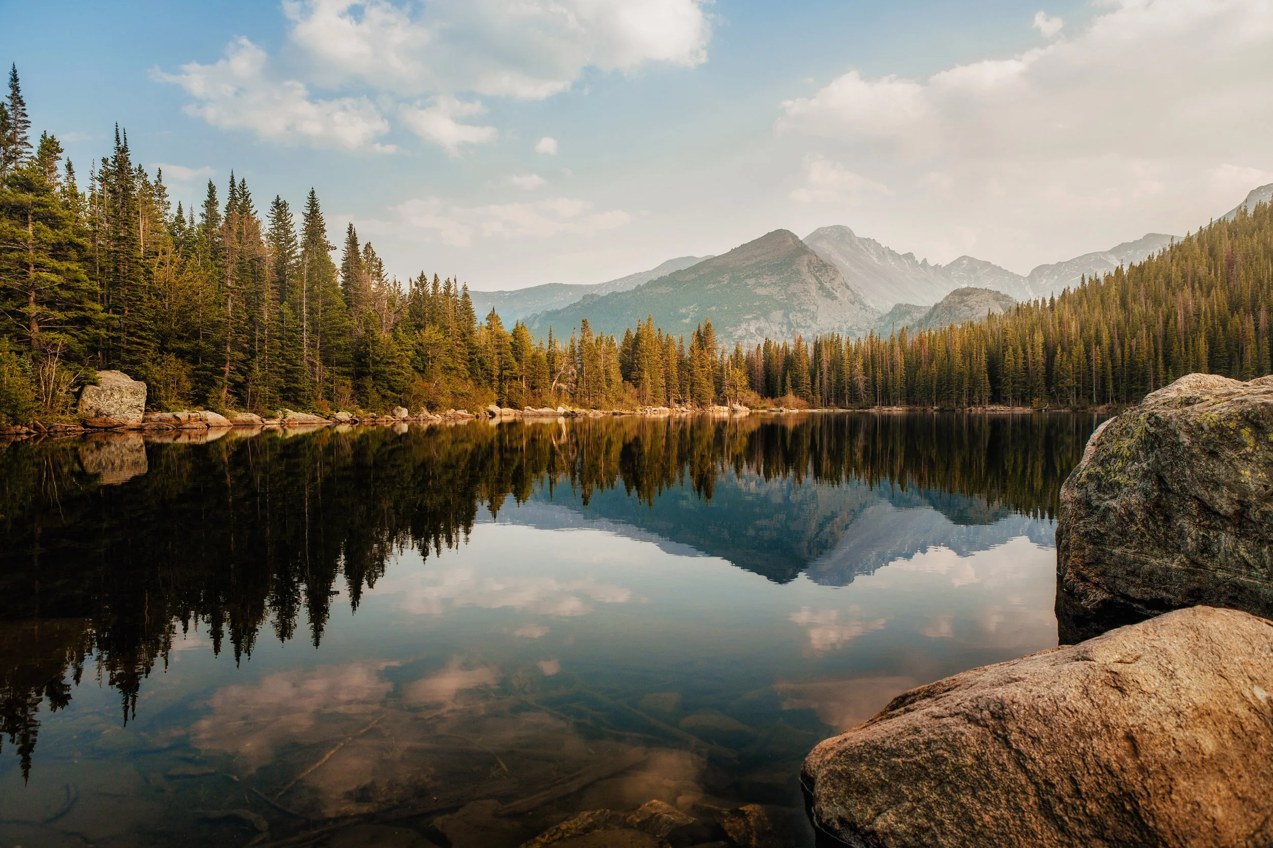 Peaks and pine forest reflected in the calm water of Bear Lake at sunset, Rocky Mountain National Park, Colorado, by Ryan L. Smith