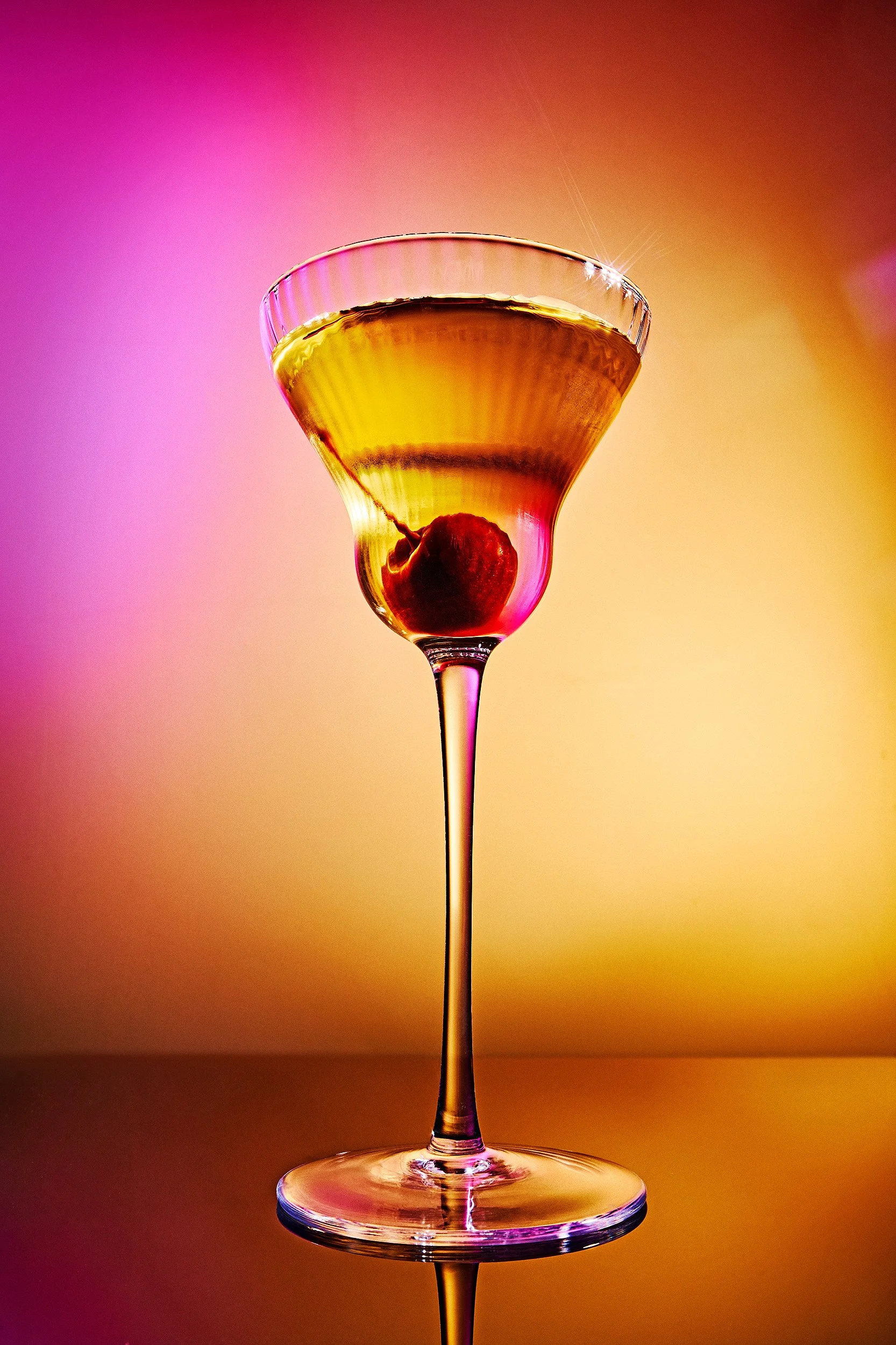 Manhattan cocktail with cherry garnish and pink gel lighting, beverage photography by Ryan L. Smith