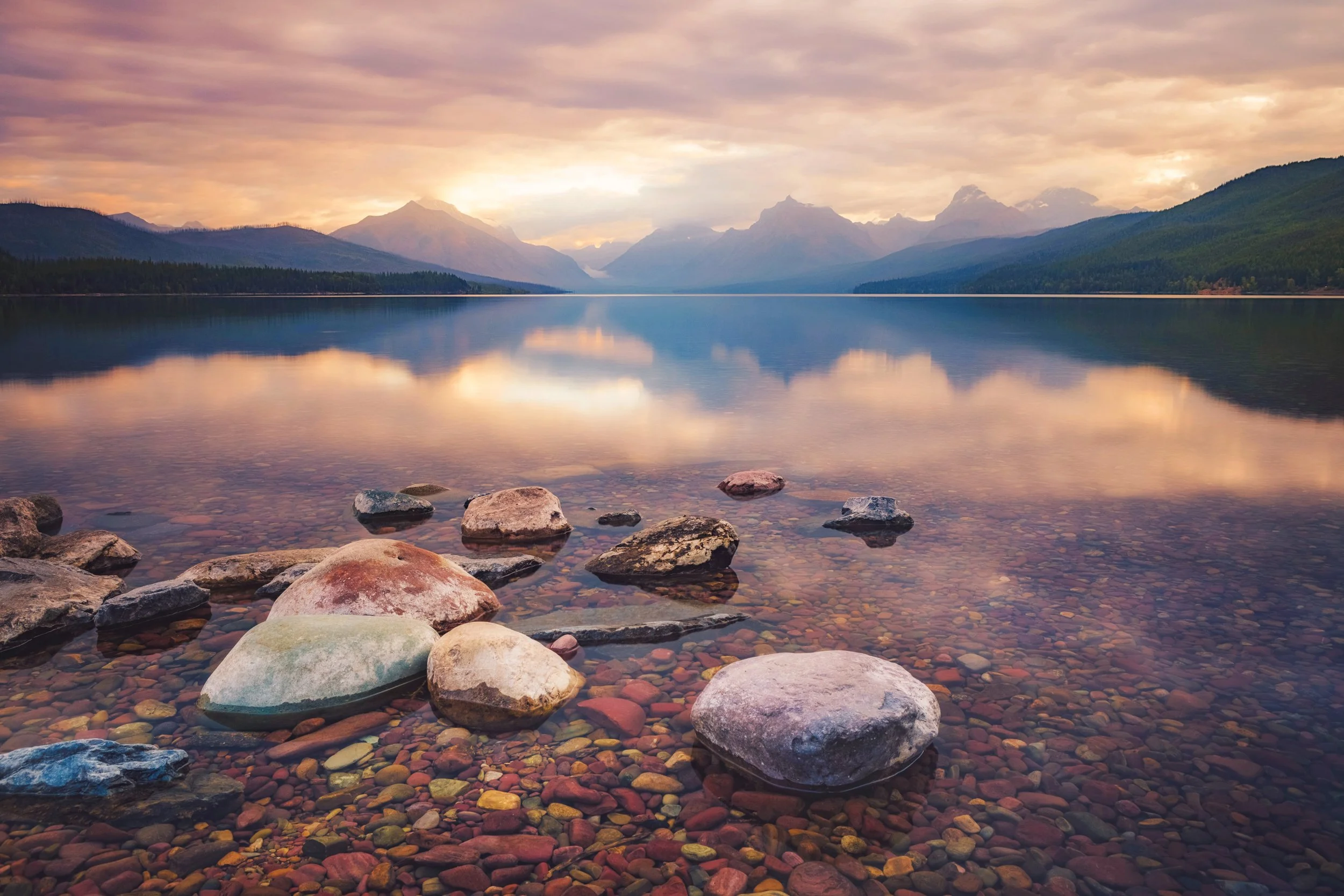 Sunrise over Lake McDonald with mountains reflected in calm water, Glacier National Park, Montana, by Ryan L. Smith
