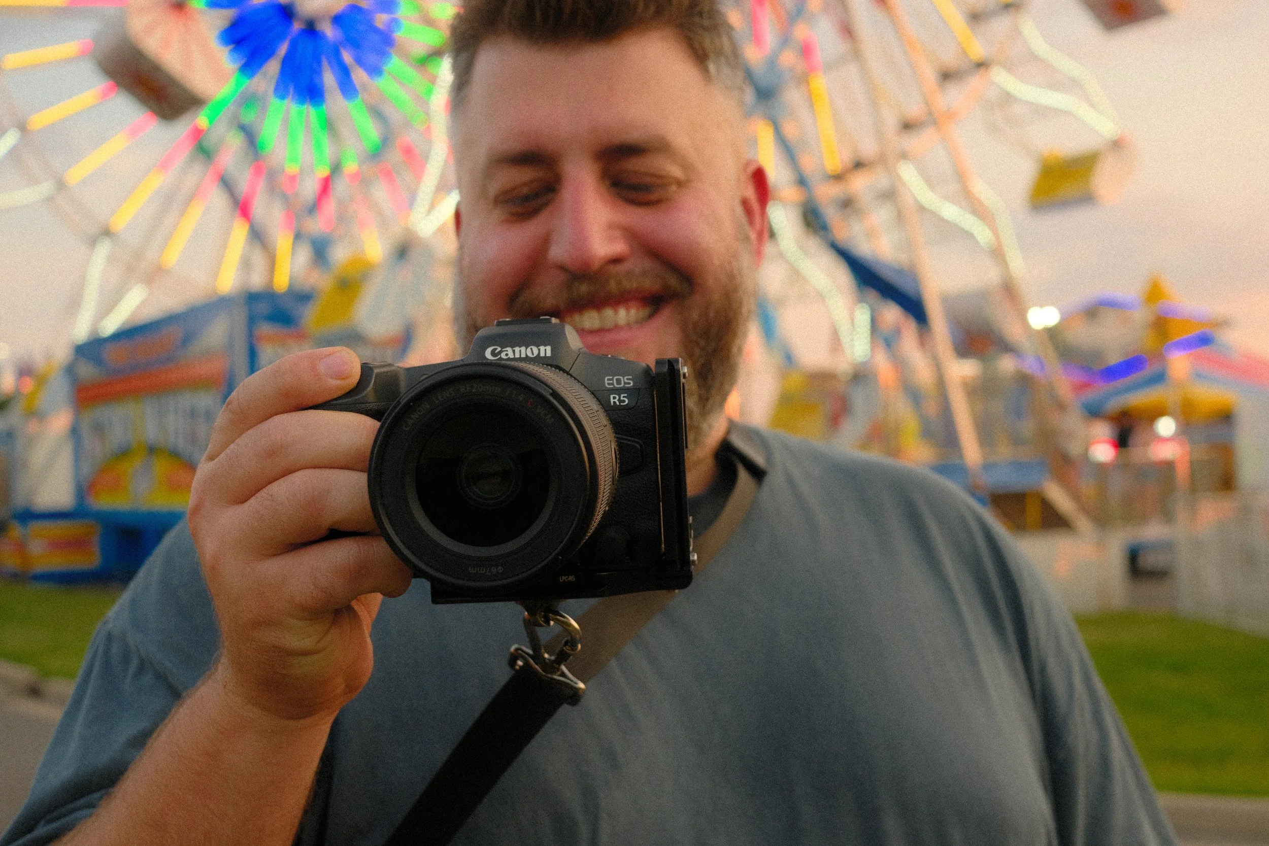 Ryan L. Smith photographing at a carnival with colorful lights in the background.