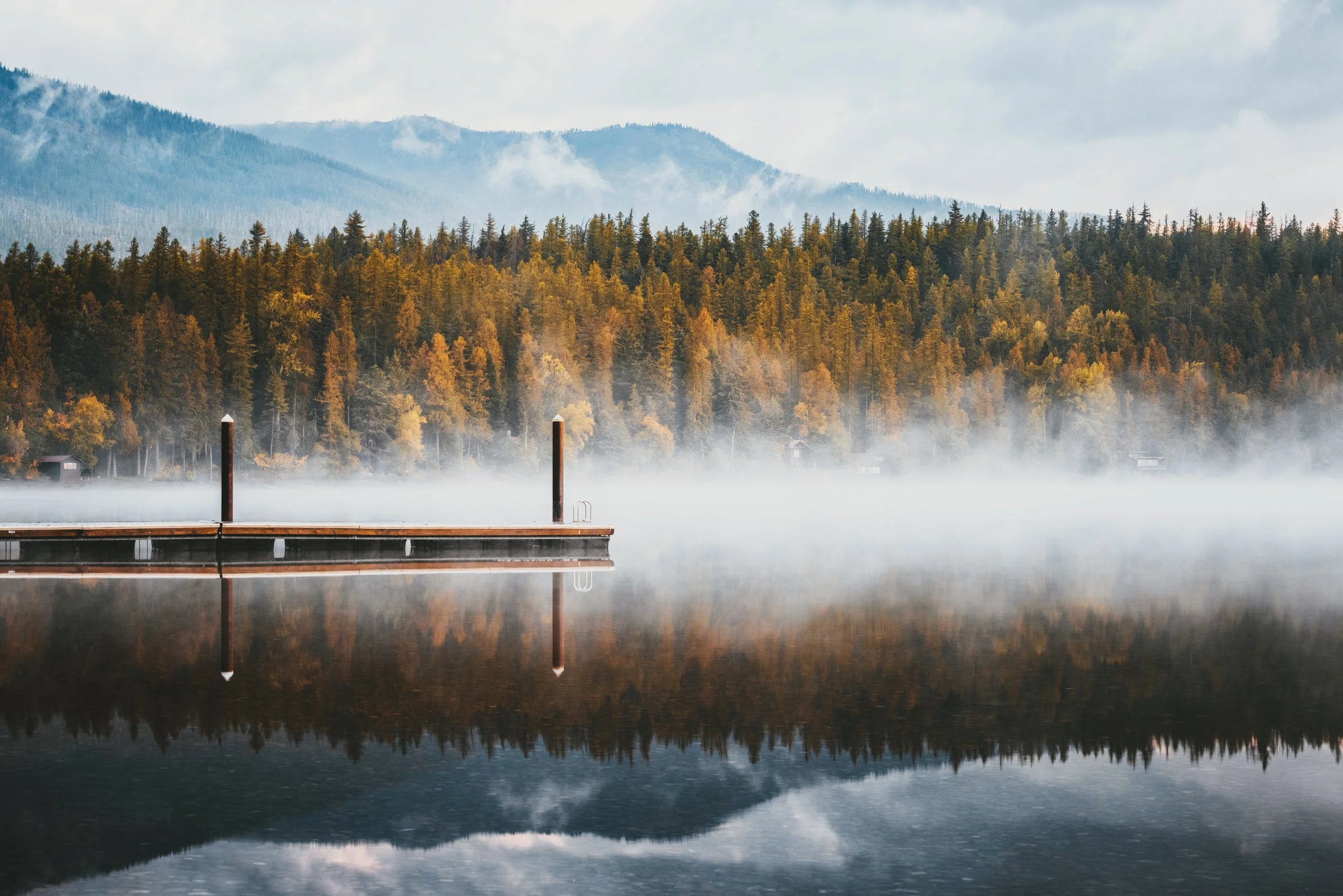 Fog hovering over the colorful pebbled shoreline of Lake McDonald, Glacier National Park, Montana, by Ryan L. Smith