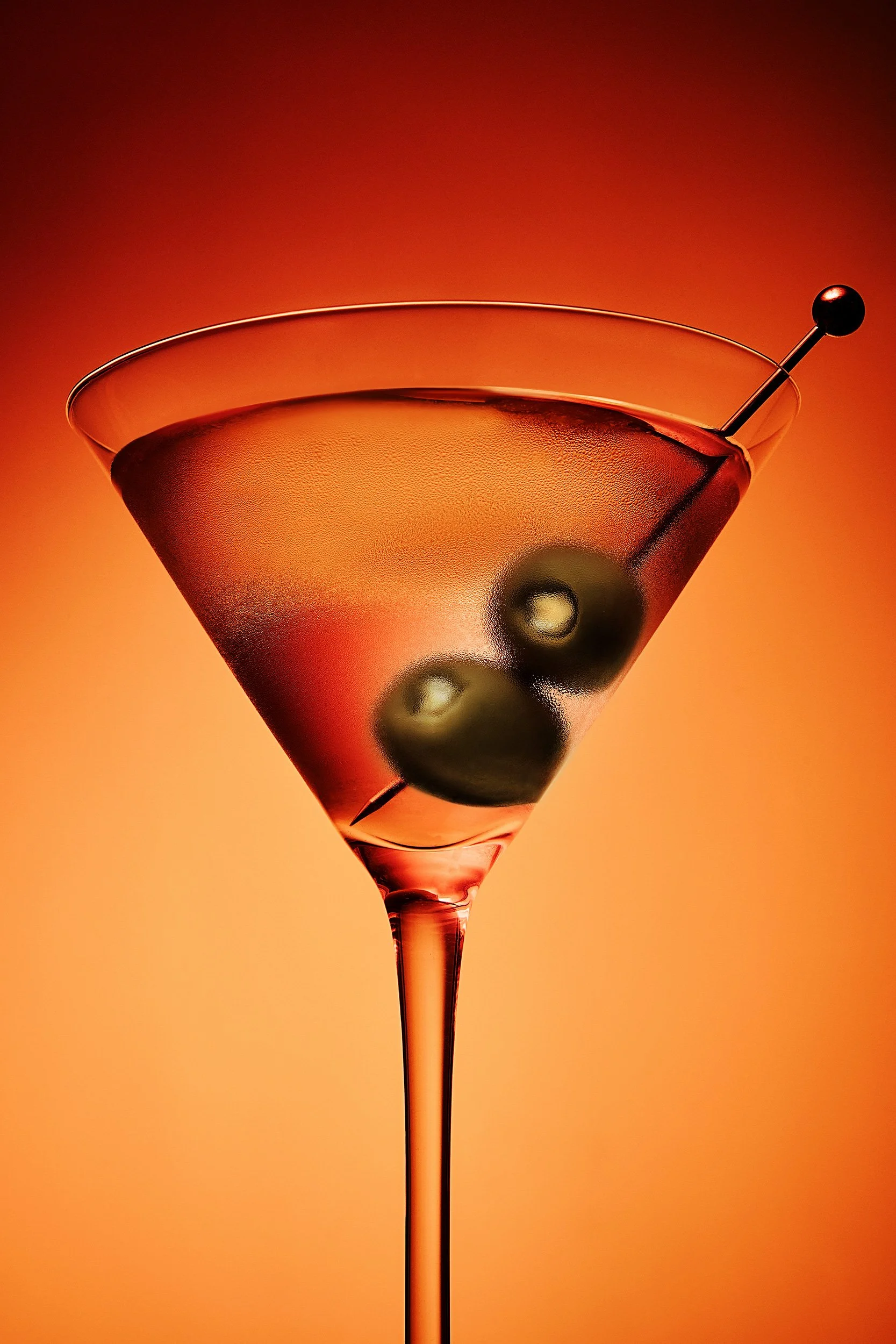 Dirty martini with olive garnish and orange gel lighting, cocktail photography by Ryan L. Smith