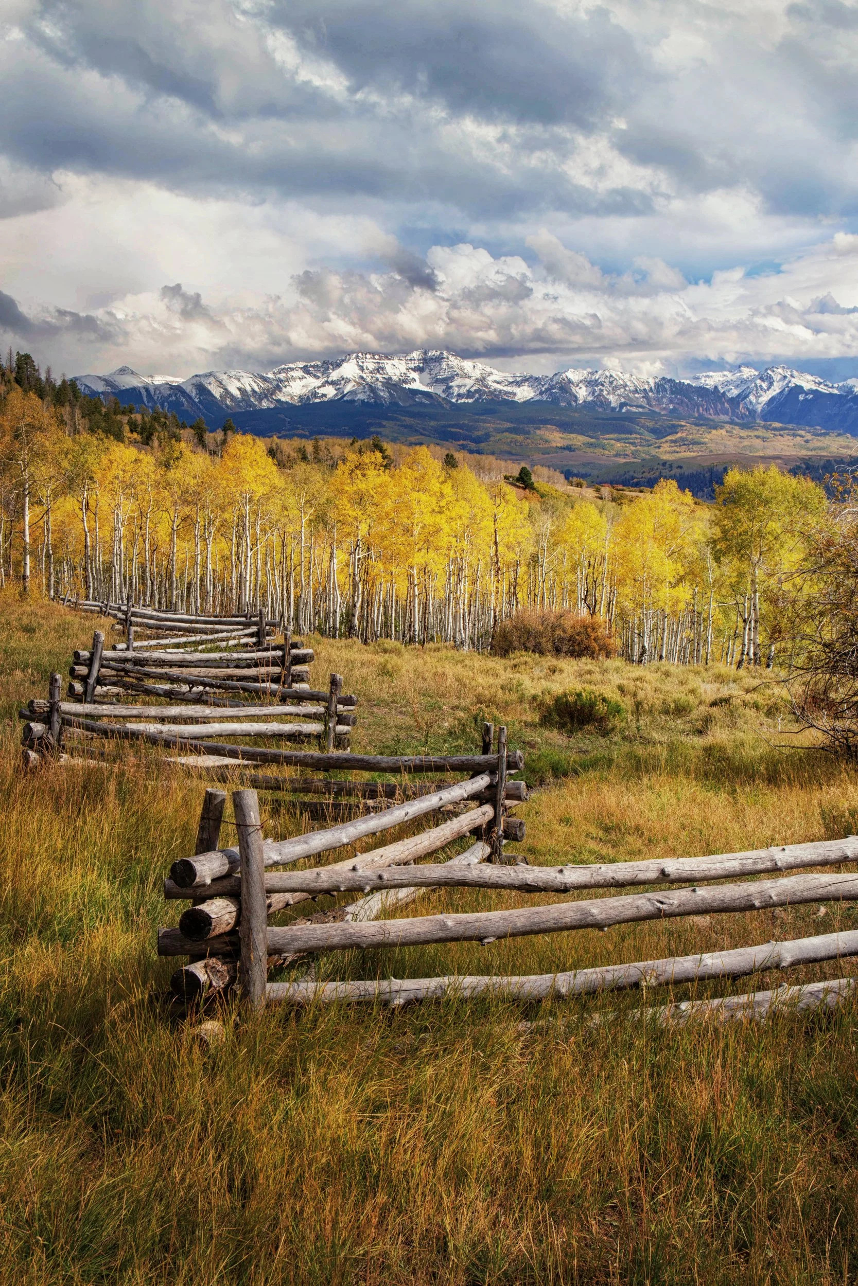 An old wooden fence leading toward golden aspens and the mountains along Last Dollar Road, Telluride, Colorado, by Ryan L. Smith