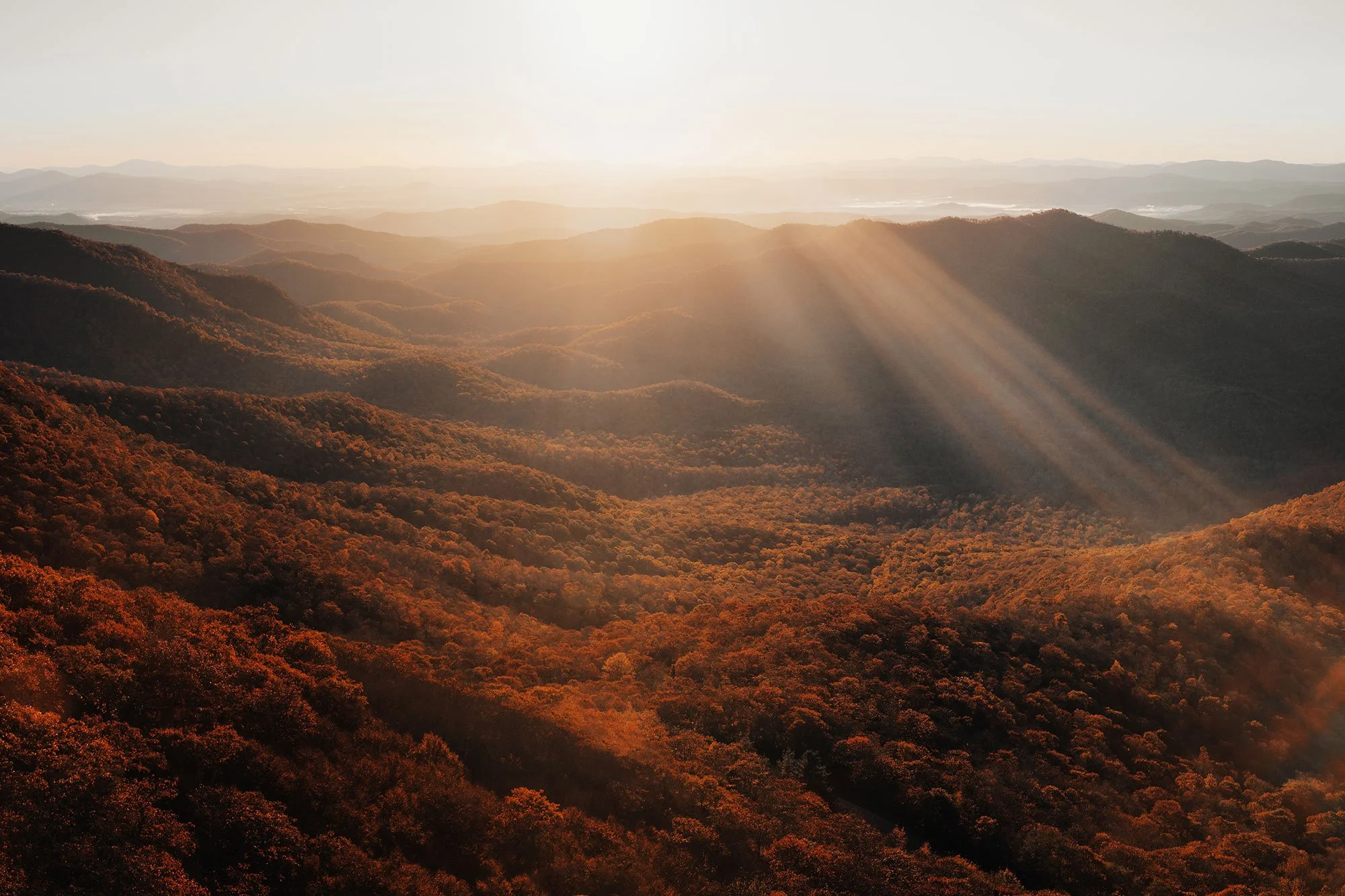 Sunbeams breaking through morning haze over the layered ridgelines of the Blue Ridge Mountains, Asheville, North Carolina, by Ryan L. Smith