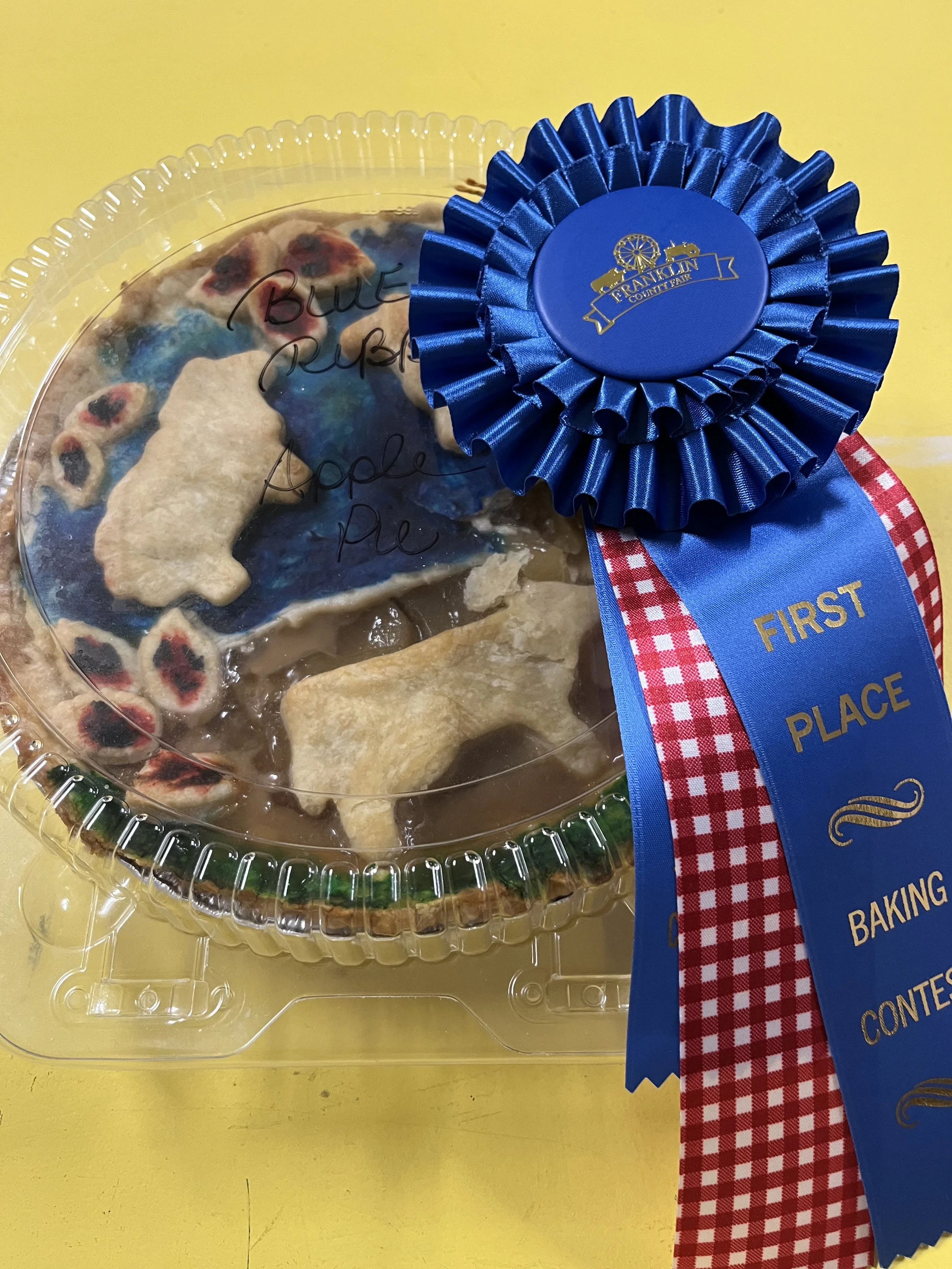 An apple pie with a blue ribbon