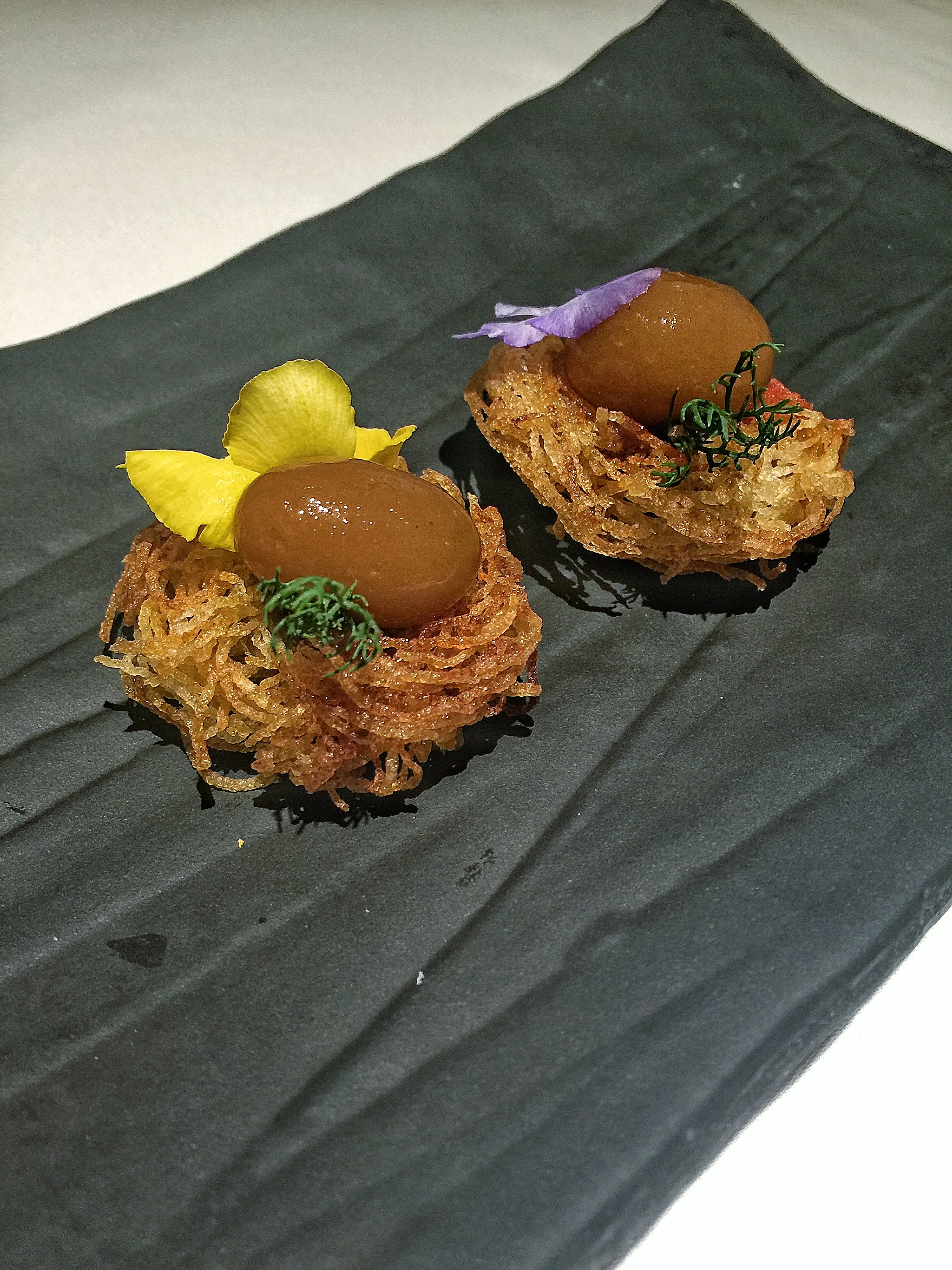 Gaggan's take on the popular Parsi dish of meat curry with potato sticks (Salli Boti) represented with a lamb curry chutney sphere sitting atop a fried potato nest.