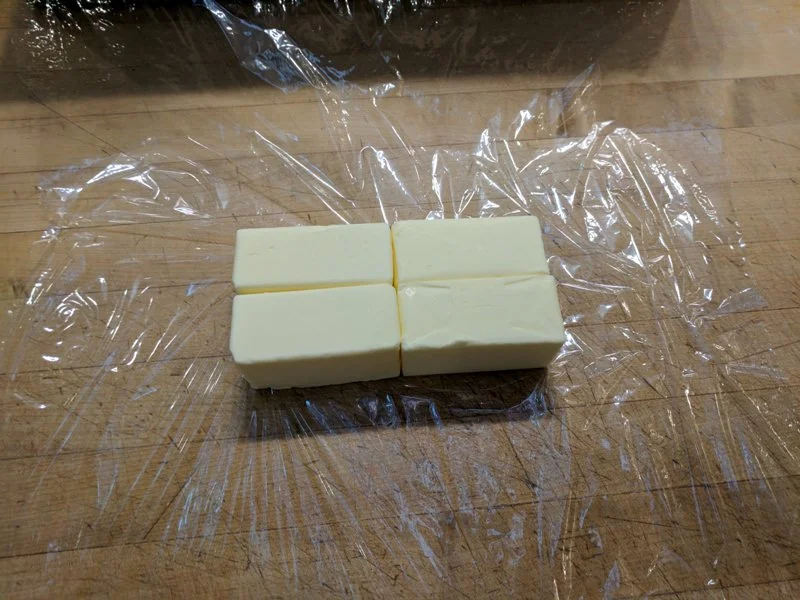 Place four sticks of butter in middle of plastic wrap to begin making your croissant butter block.