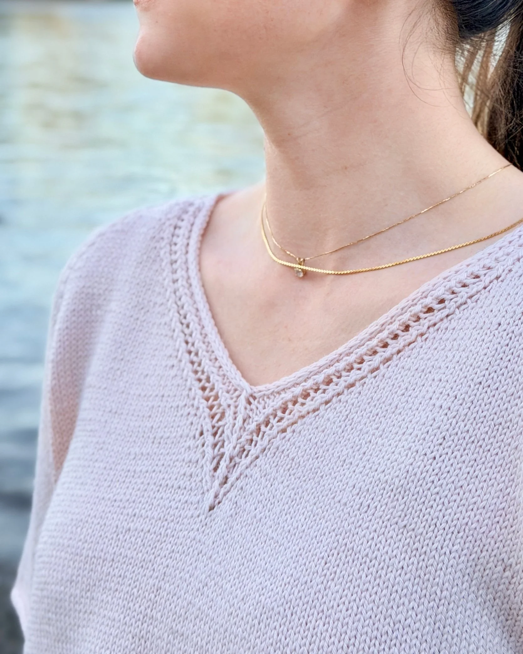 Classic Lace Tee, a V-Neck Knit Top / Pullover / Sweater Pattern in a blush colored yarn by Rosy Green Wool on model in front of river