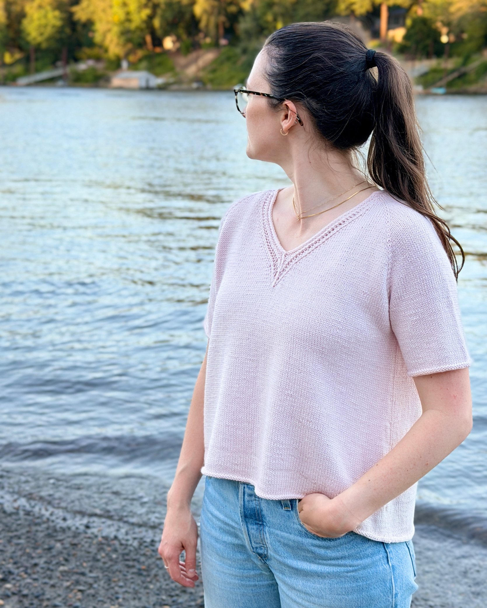 Classic Lace Tee, a V-Neck Knit Top / Pullover / Sweater Pattern in a blush colored yarn by Rosy Green Wool on model in front of river