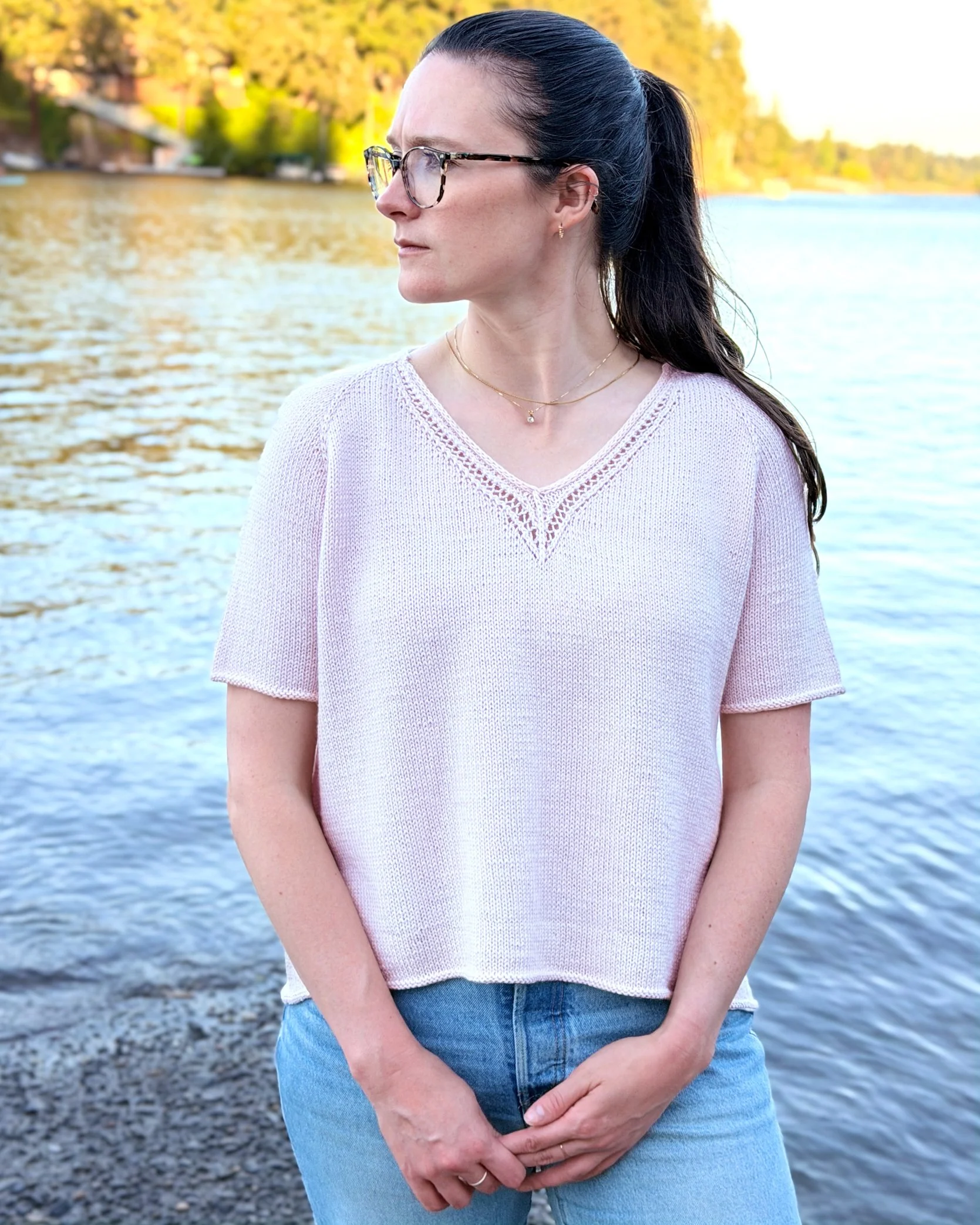Classic Lace Tee, a V-Neck Knit Top / Pullover / Sweater Pattern in a blush colored yarn by Rosy Green Wool on model in front of river